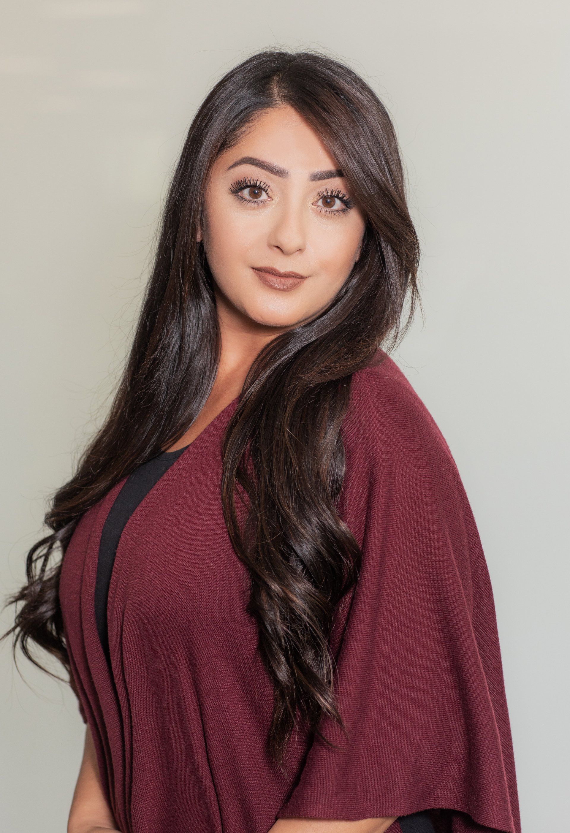 A woman with long hair is wearing a maroon sweater.