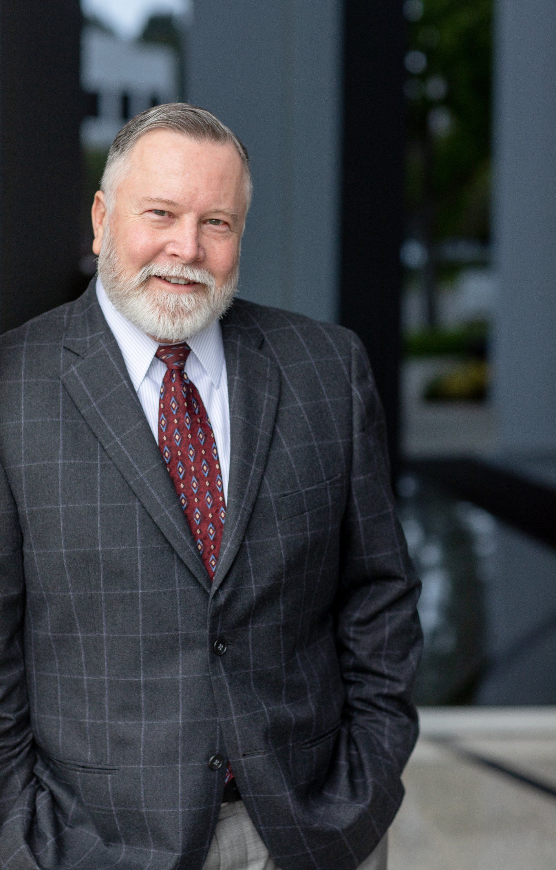 A man in a suit and tie is standing with his hands in his pockets.