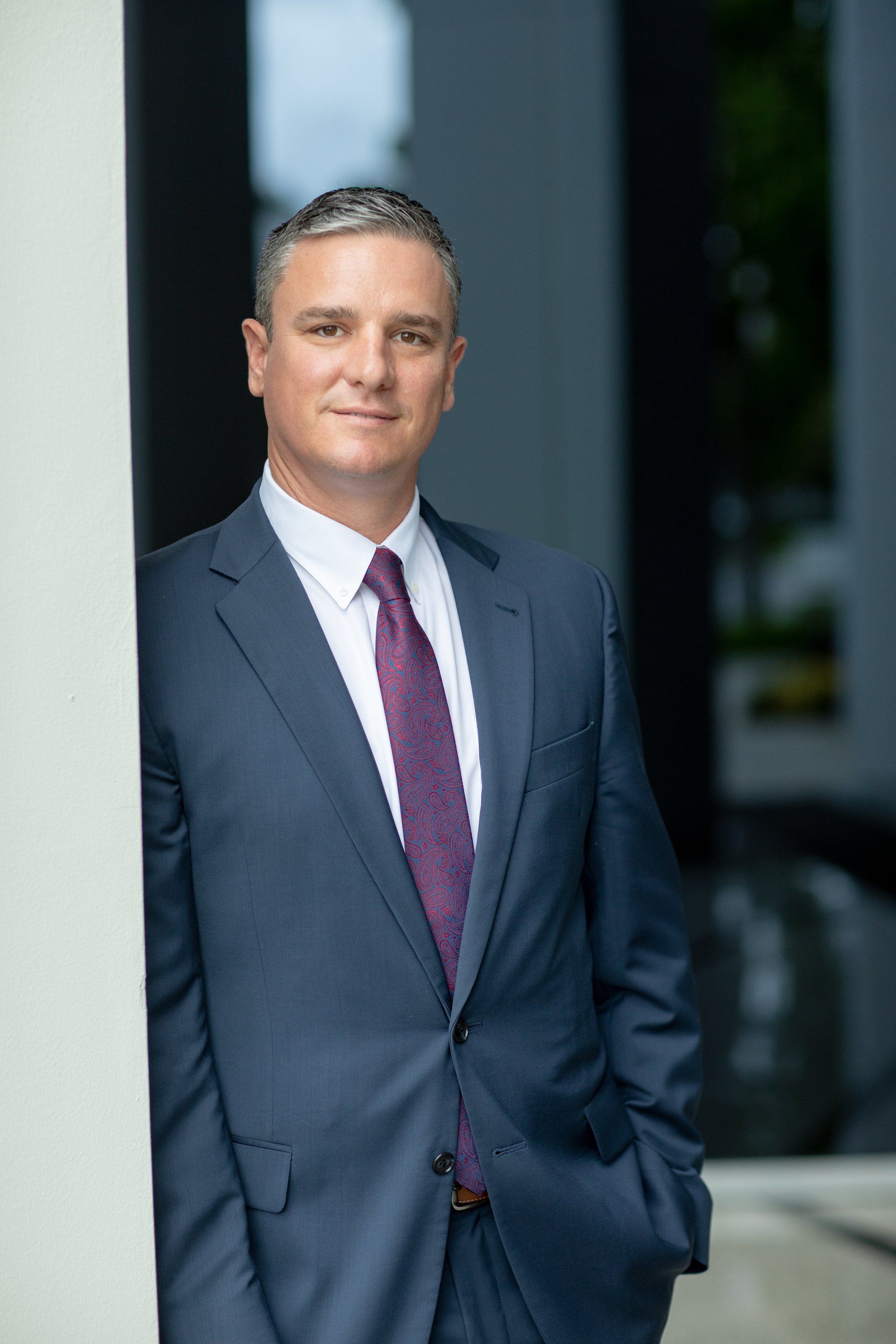 A man in a suit and tie is leaning against a wall.