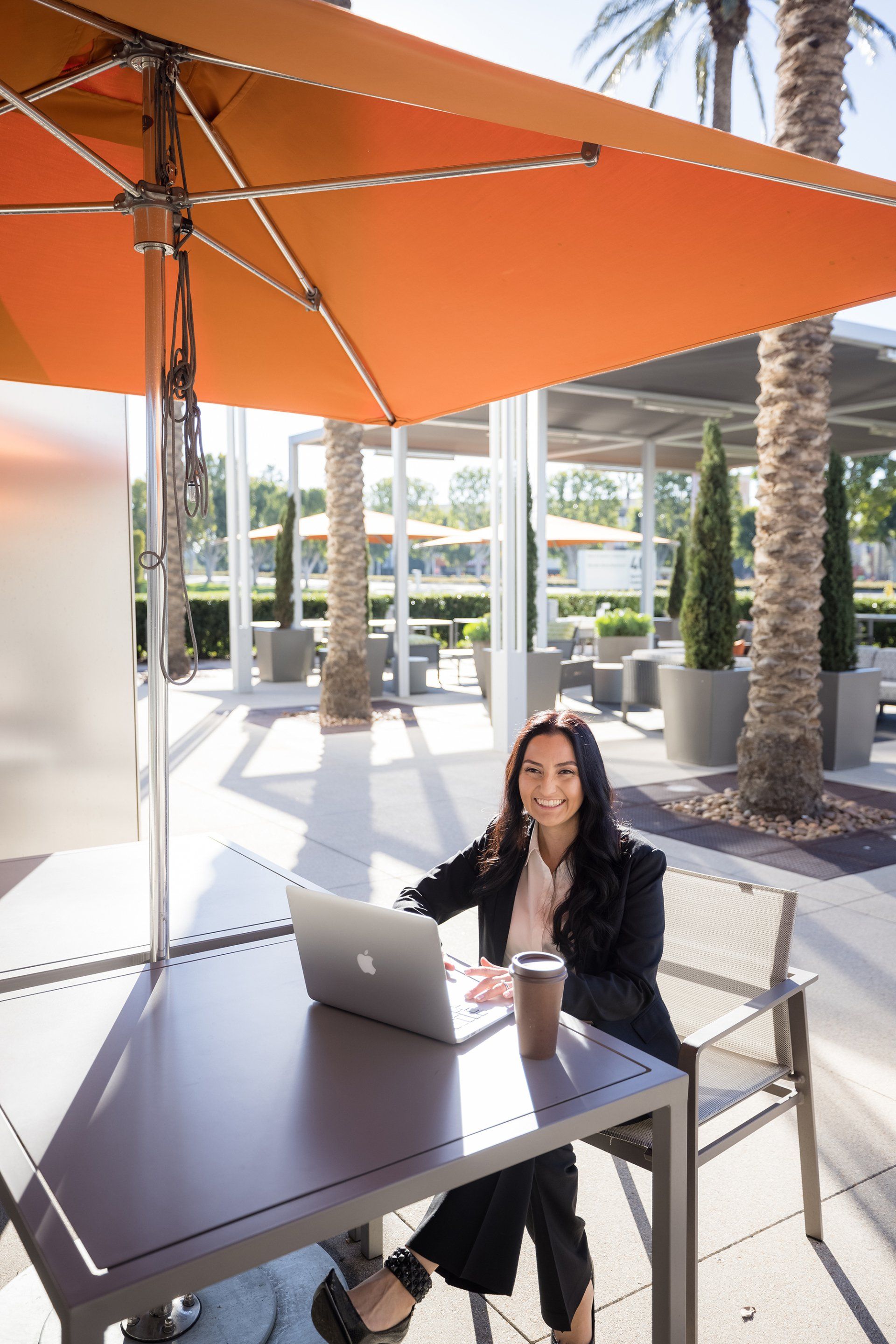 A woman is sitting at a table with a laptop and a cup of coffee.