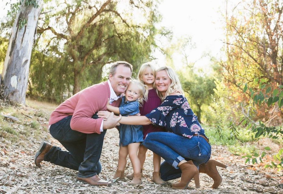 A family is posing for a picture in the woods.