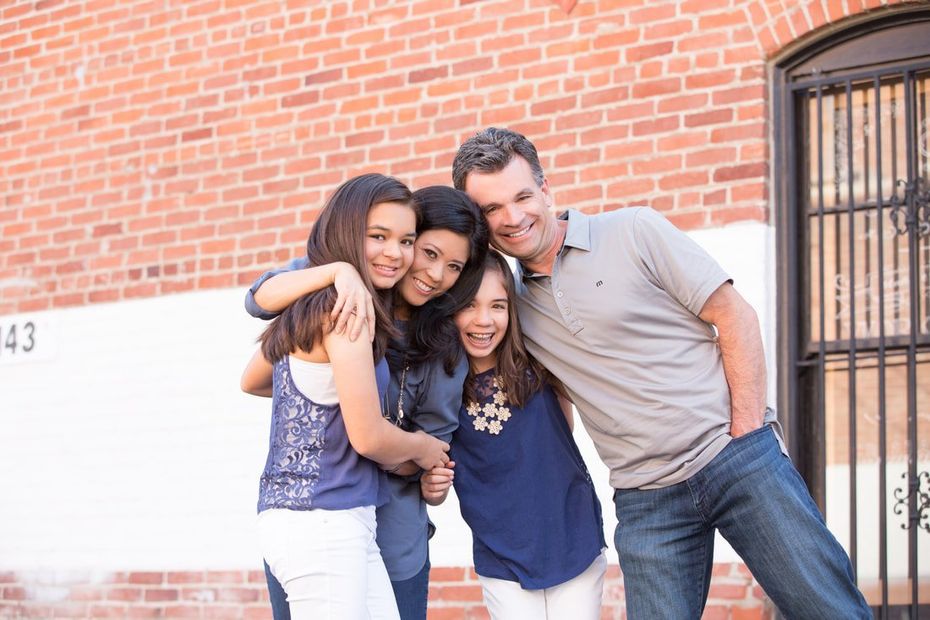 A family is posing for a picture in front of a brick building.