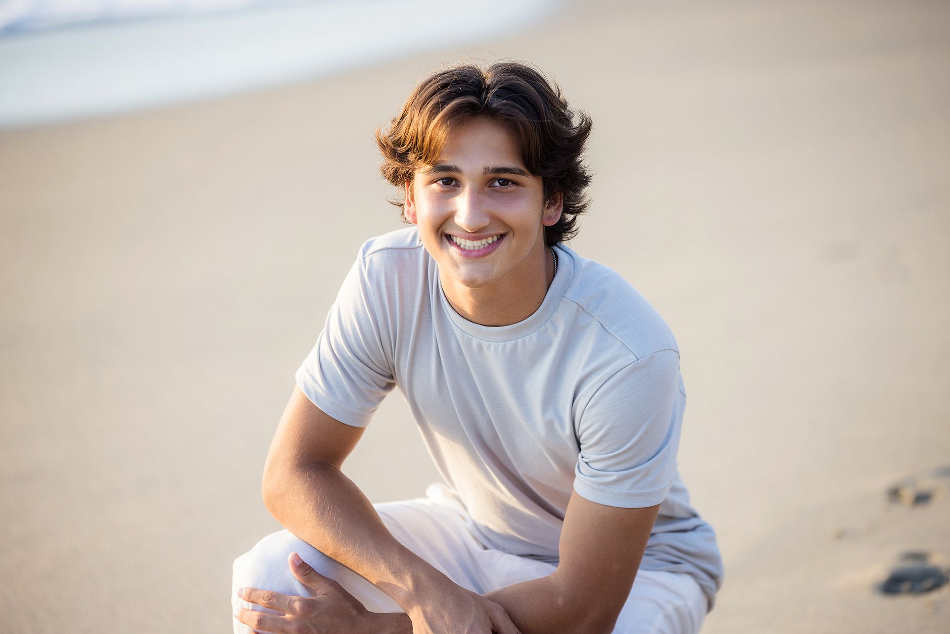 Smiling boy with hands in pockets during golden hour beach portraits in Laguna Beach by an Orange County family photographer.
