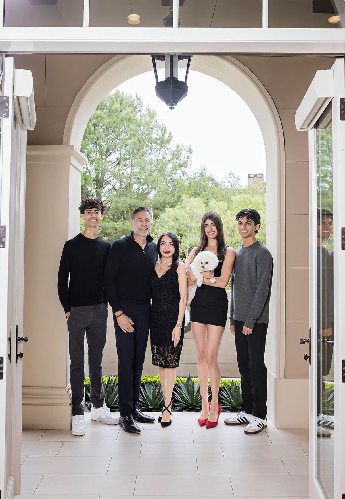 Beautiful in-home family portrait under a grand arched entryway, showcasing luxury family photography in Newport Coast by Blue Sky's Studio.