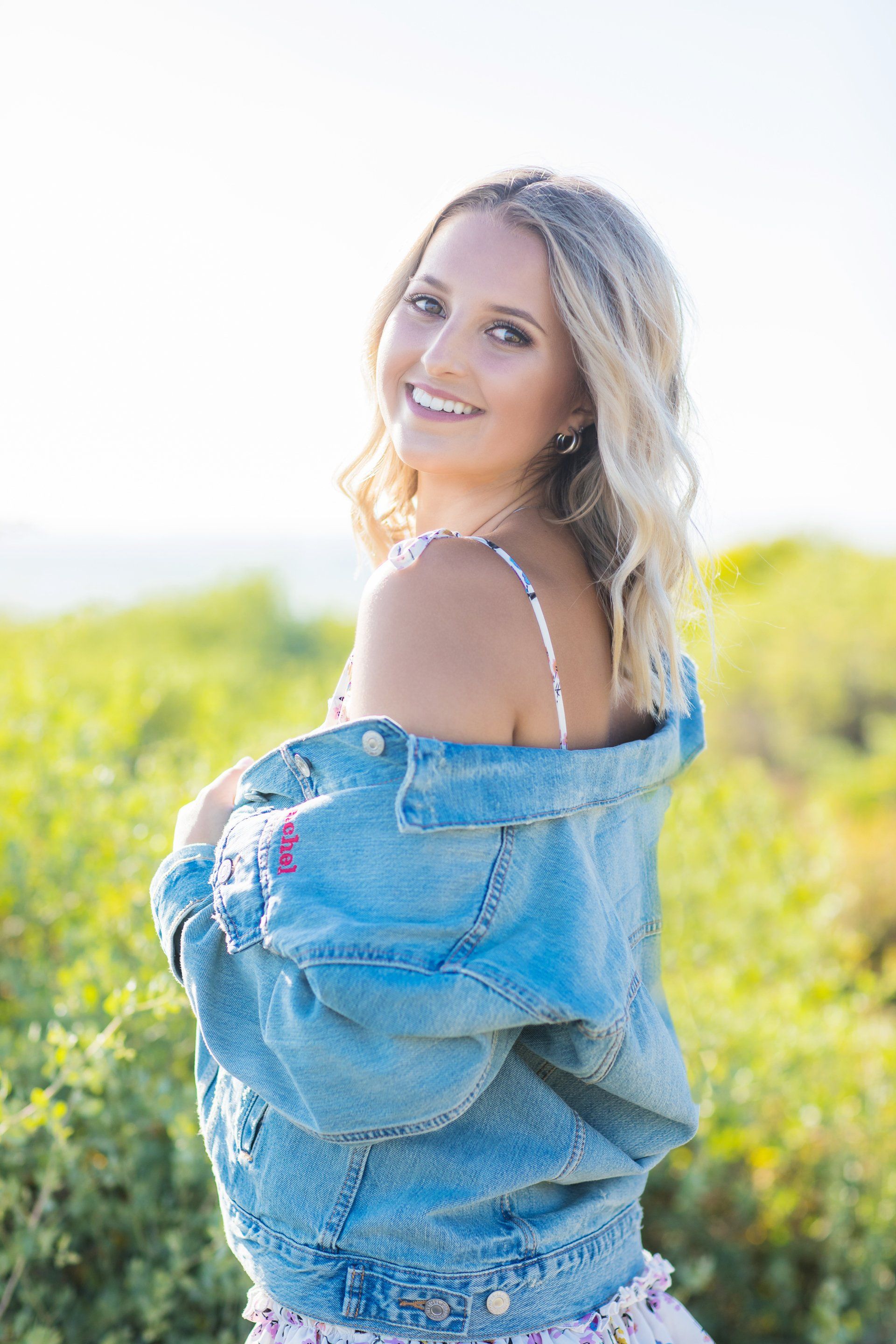 A woman in a denim jacket is standing in a field.