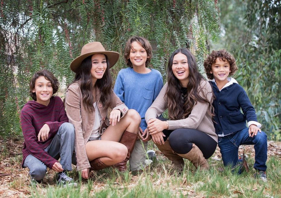 A group of people are posing for a picture in the woods.