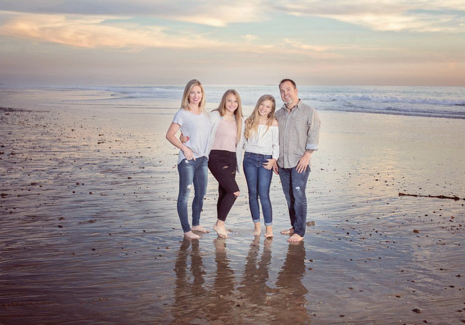 A family is posing for a picture on the beach.