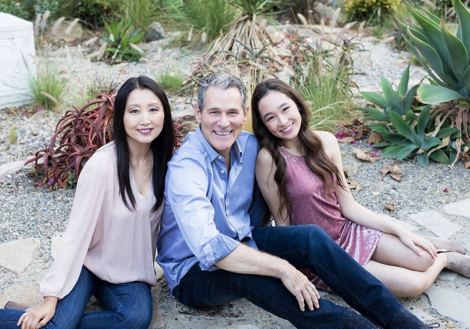 A man and two women are sitting on the ground posing for a picture.