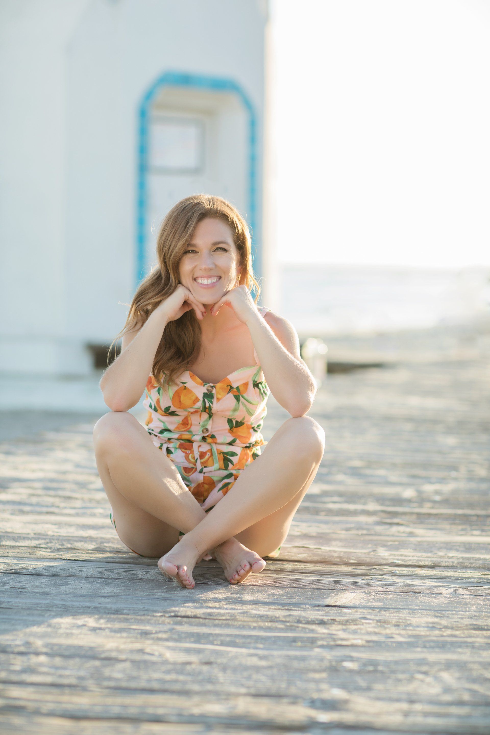 A woman in a bathing suit is squatting on a wooden dock.