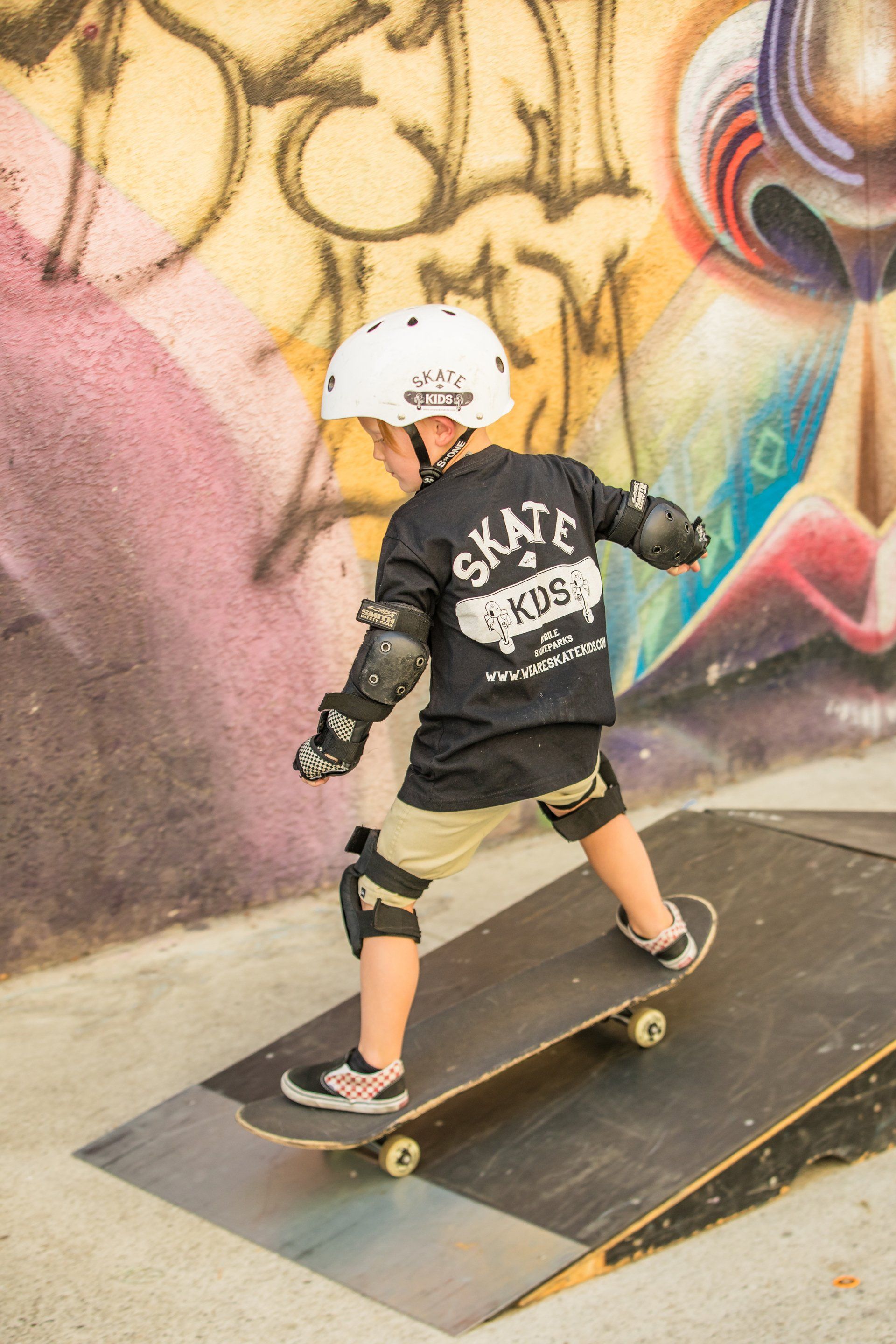 A young boy is riding a skateboard down a ramp.