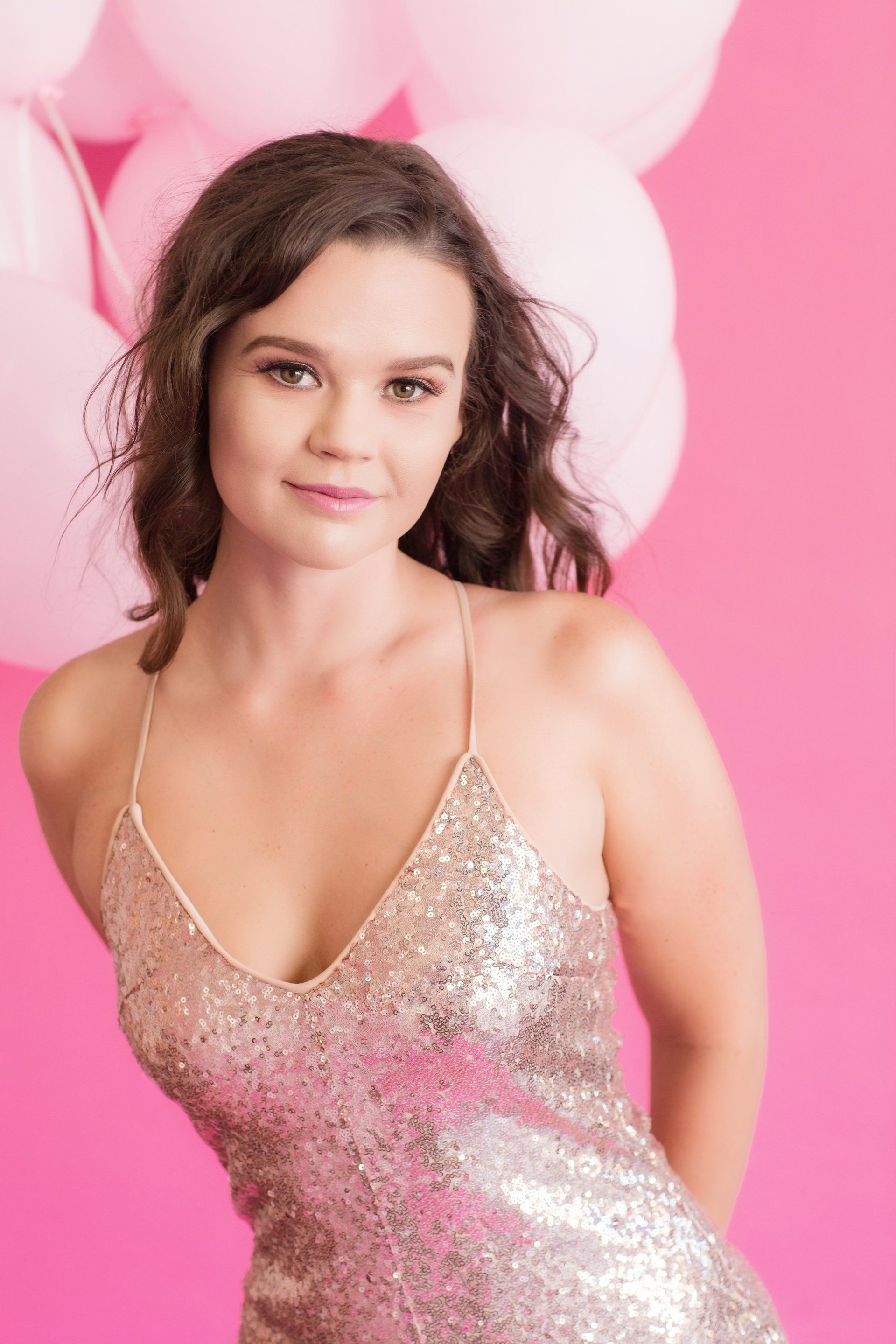 A woman looking at the camera with a pink background