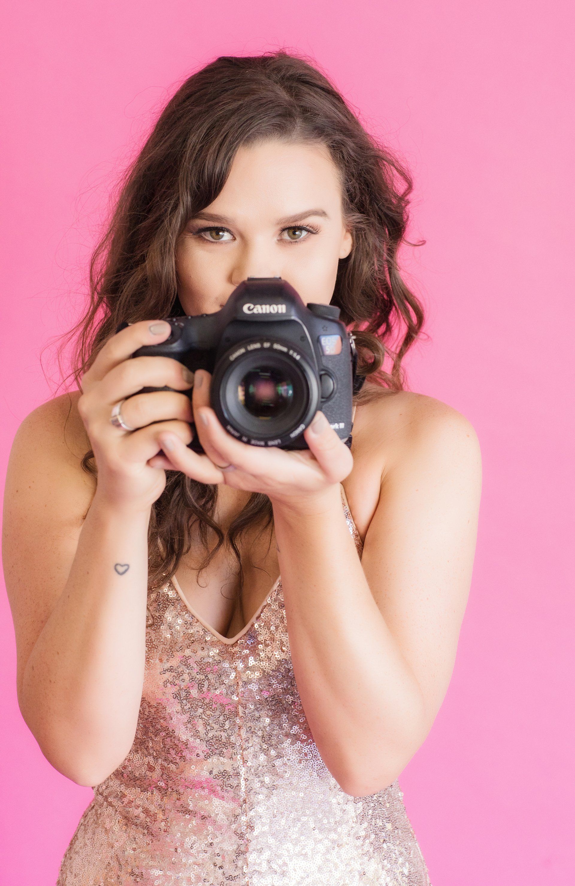 A woman is holding a camera in front of her face.