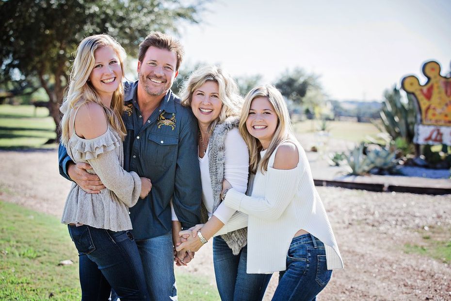 A family is posing for a picture together in front of a sign.