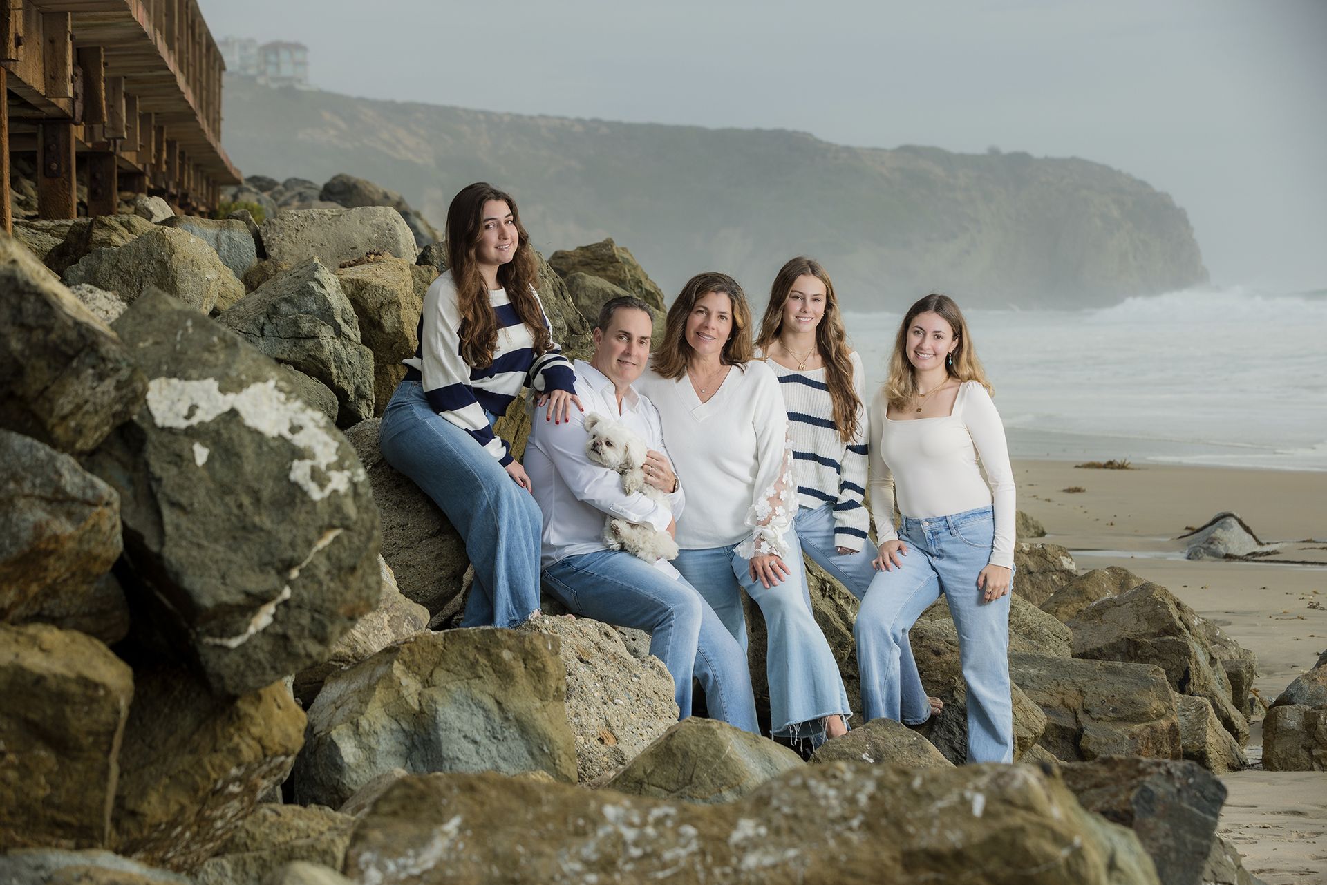 Family posing on the rocks at Salt Creek as the sun in setting wearing white and navy striped outfits.