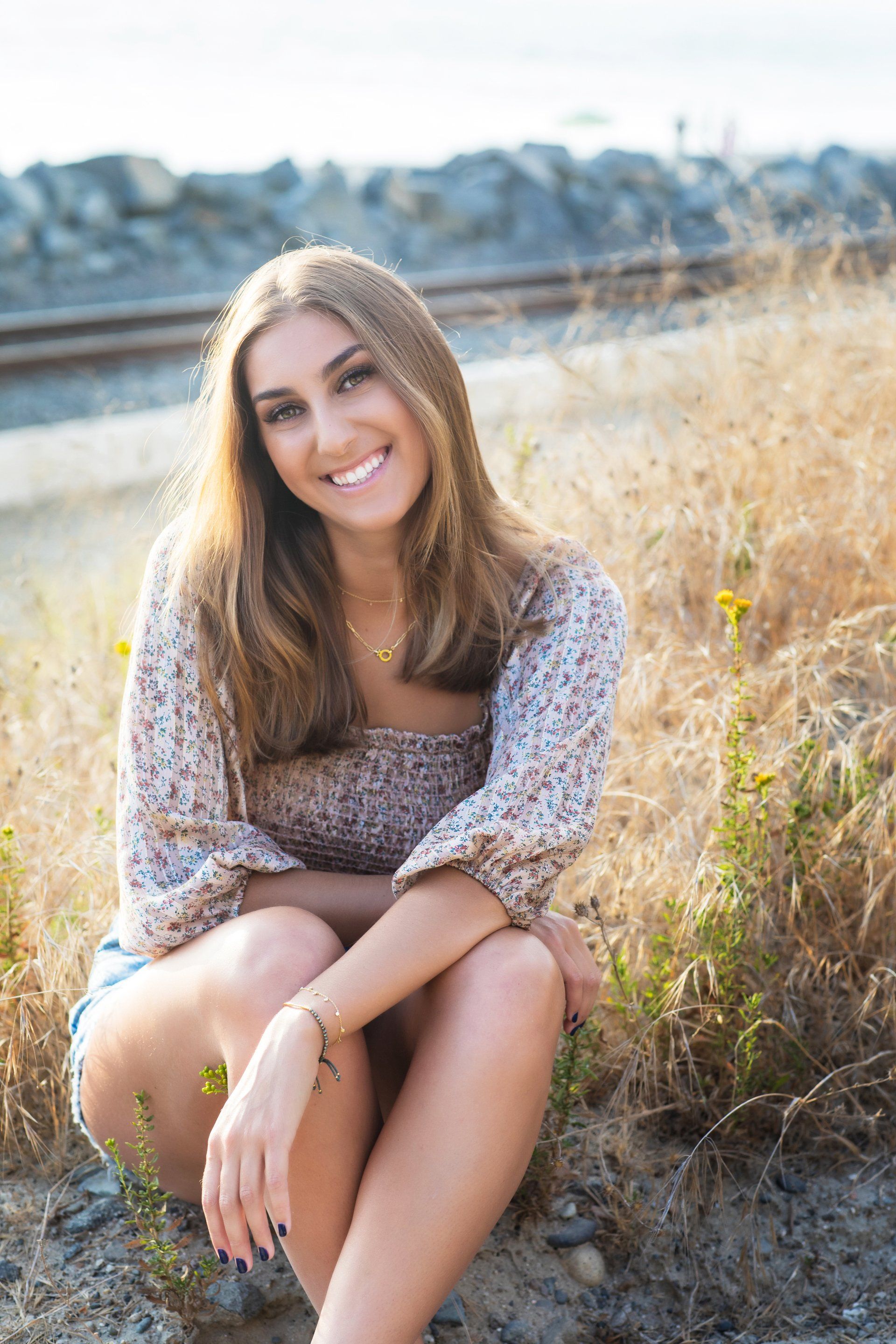 A young woman is sitting on the ground in a field.