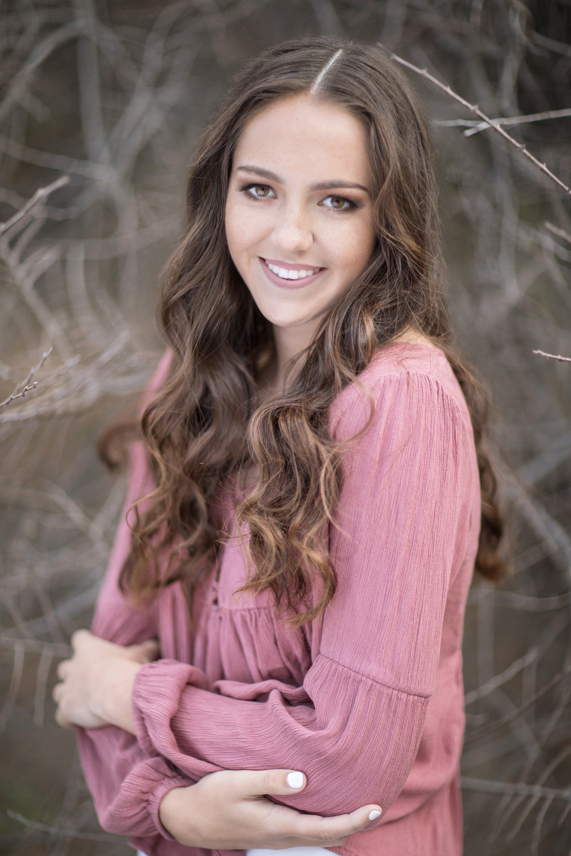 The girl is wearing a pink shirt and smiling for the camera.