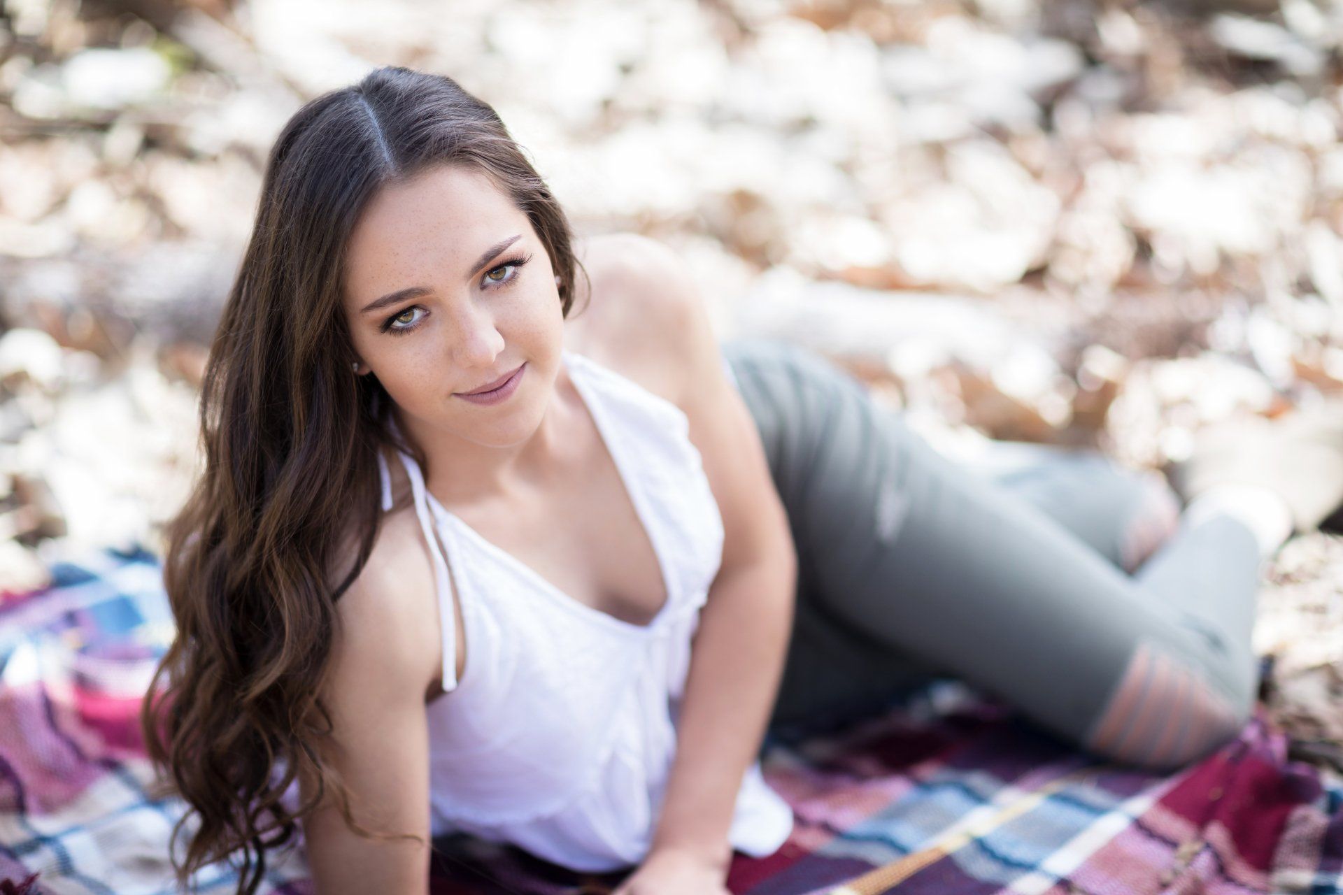 A woman is laying on a blanket in the woods.