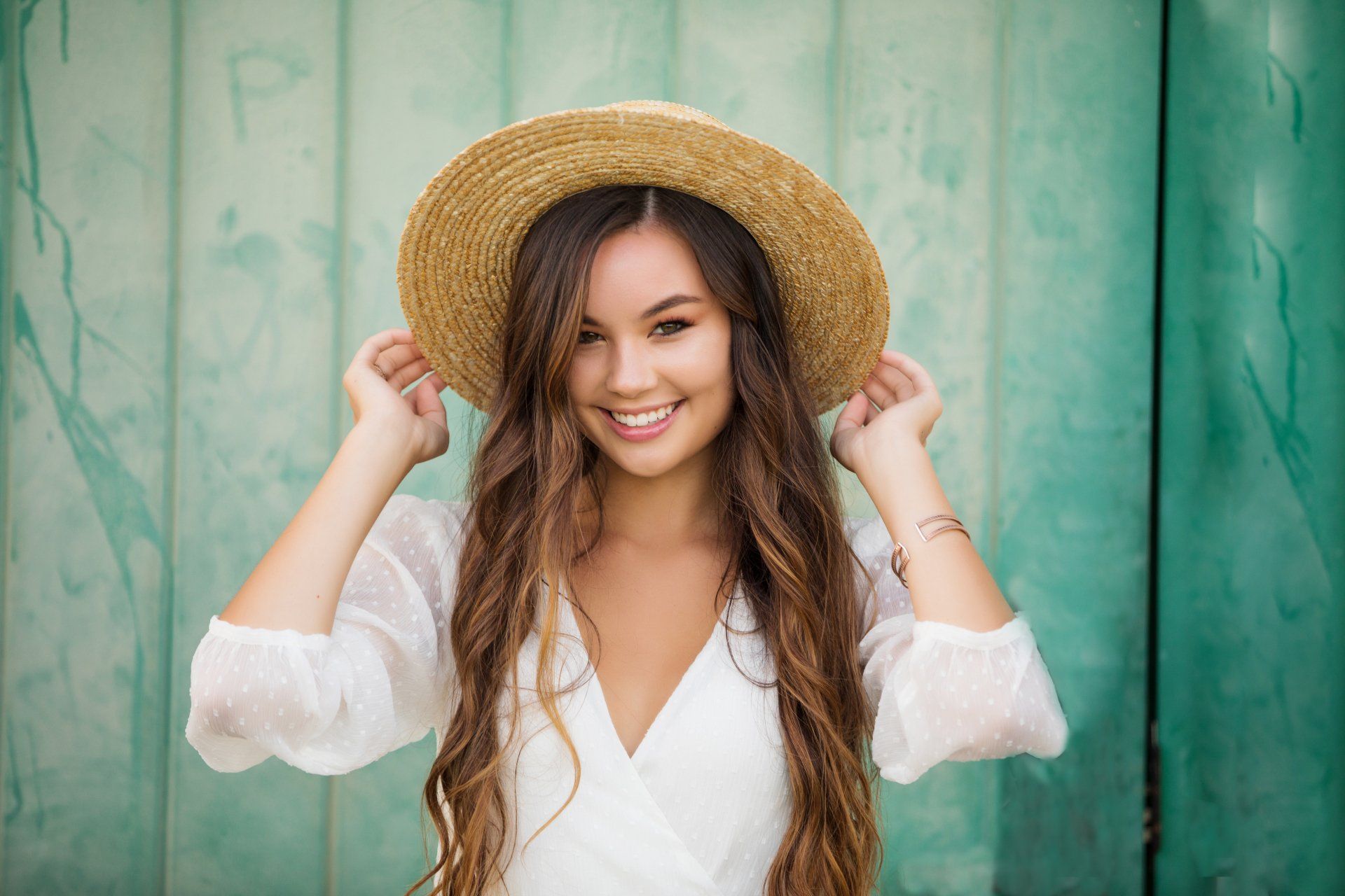 The woman is wearing a straw hat and a white dress.