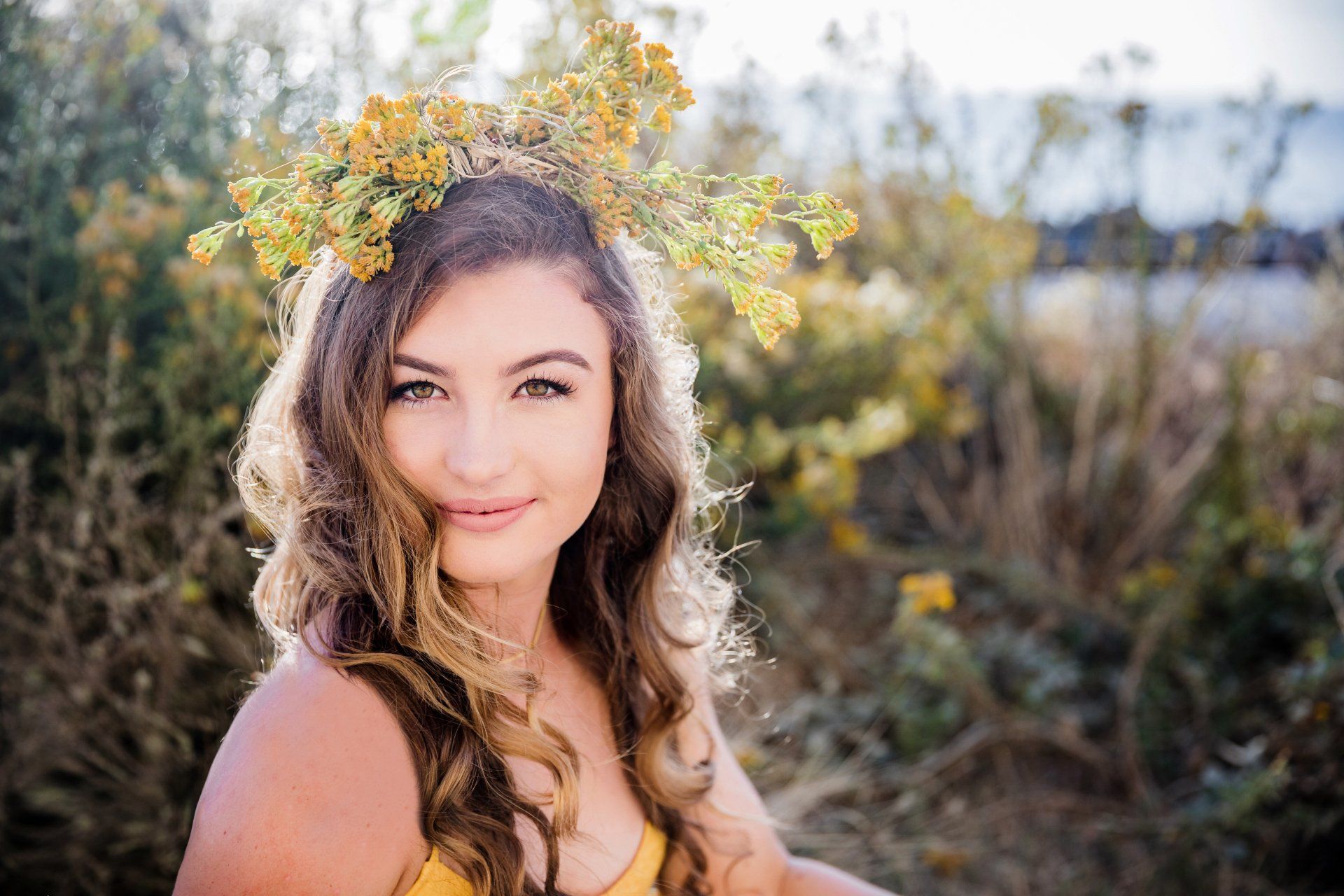 A young woman wearing a crown of yellow flowers in her hair.