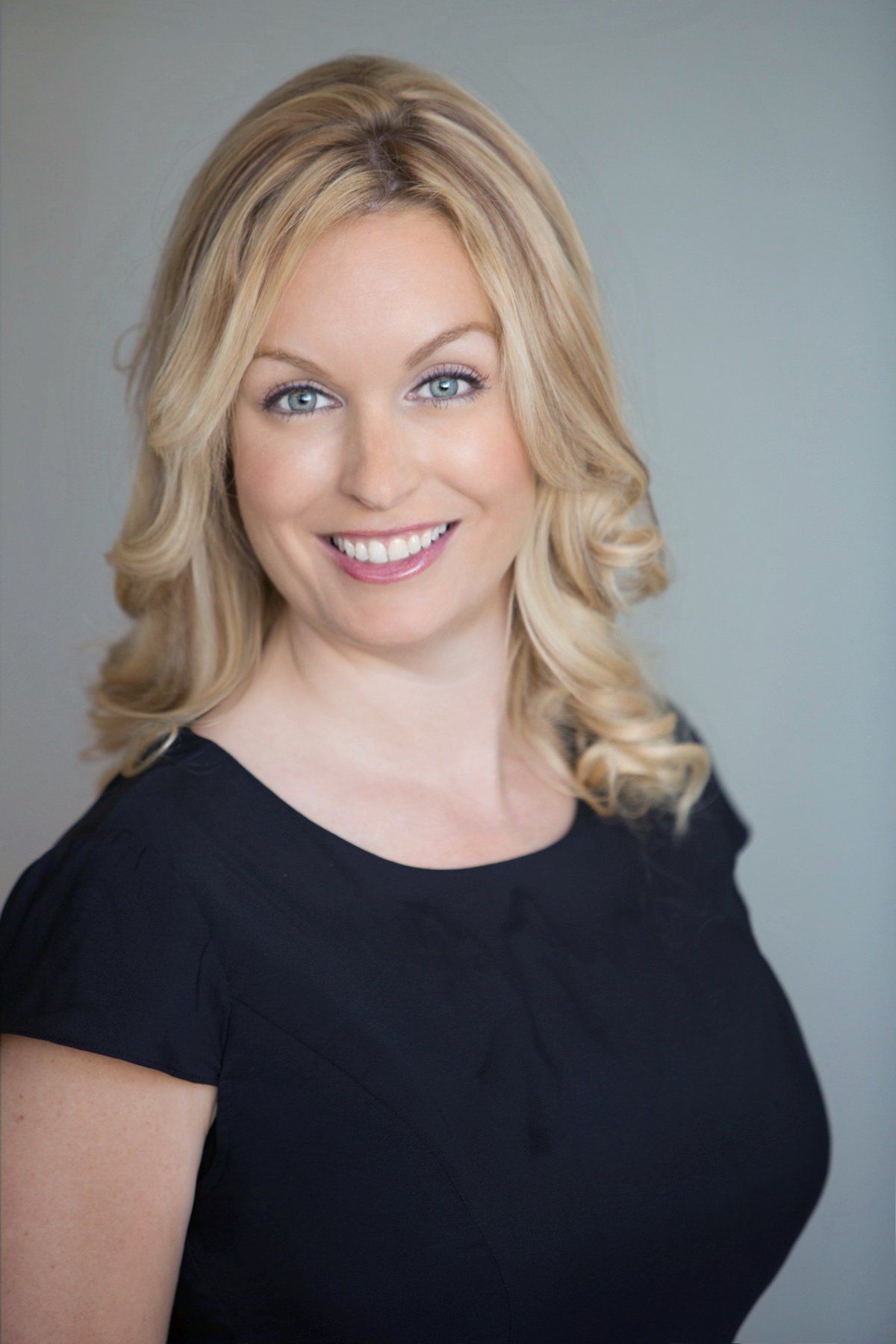 A woman in a black dress is smiling for the camera.