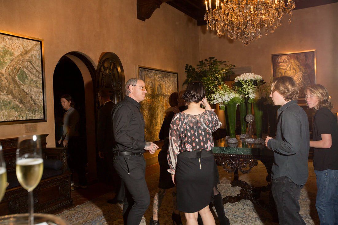 A group of people are standing in a room with a chandelier.