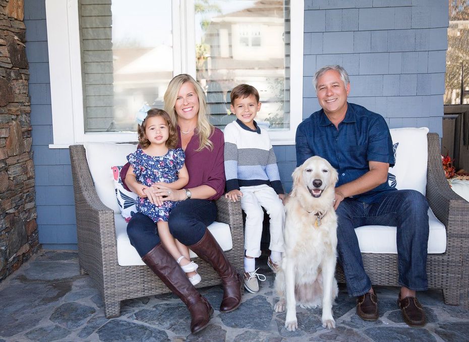 A family is sitting on a couch with a dog.