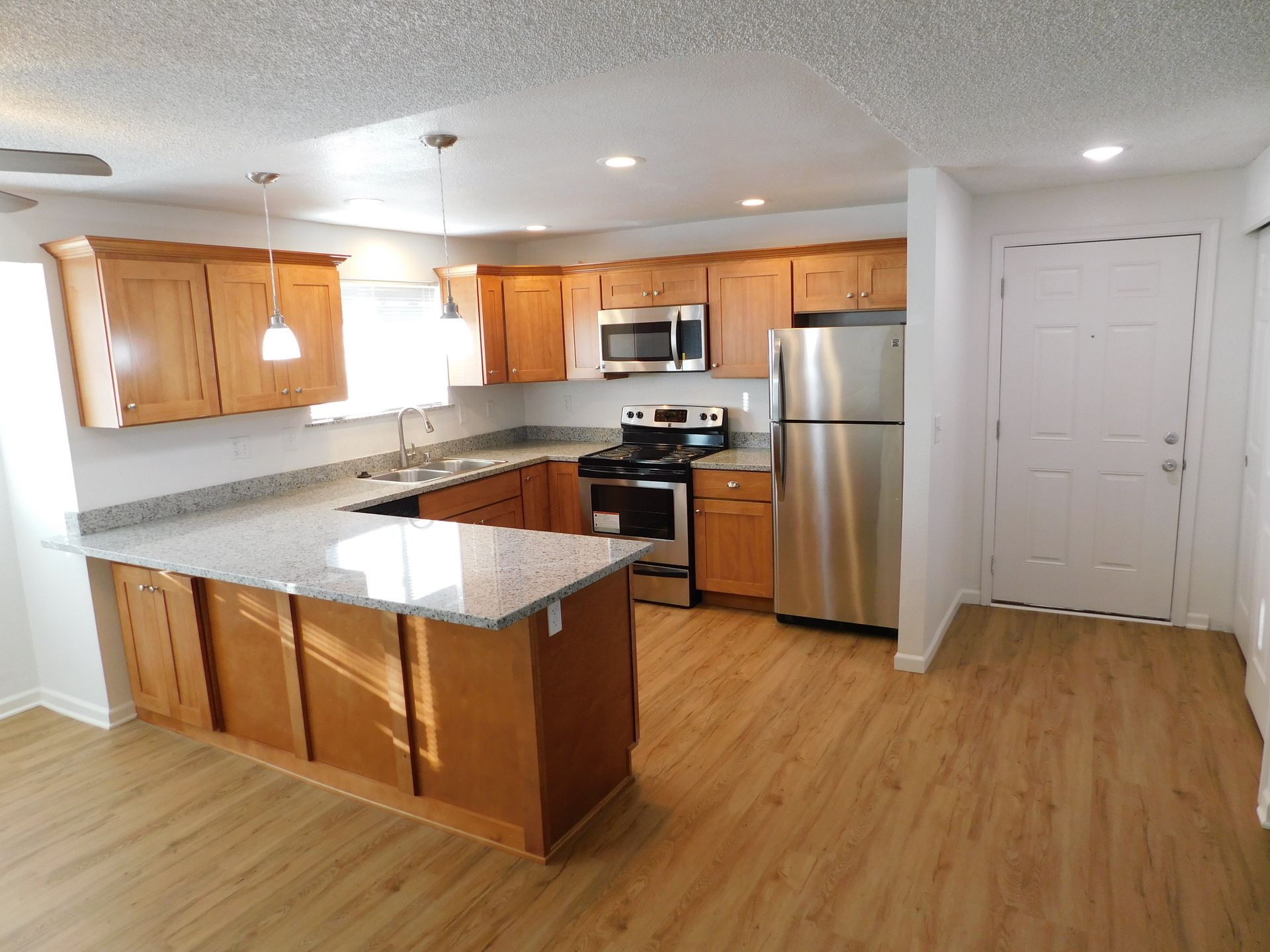 Kitchen with light wood cabinets, stainless steel appliances, and a granite countertop island.
