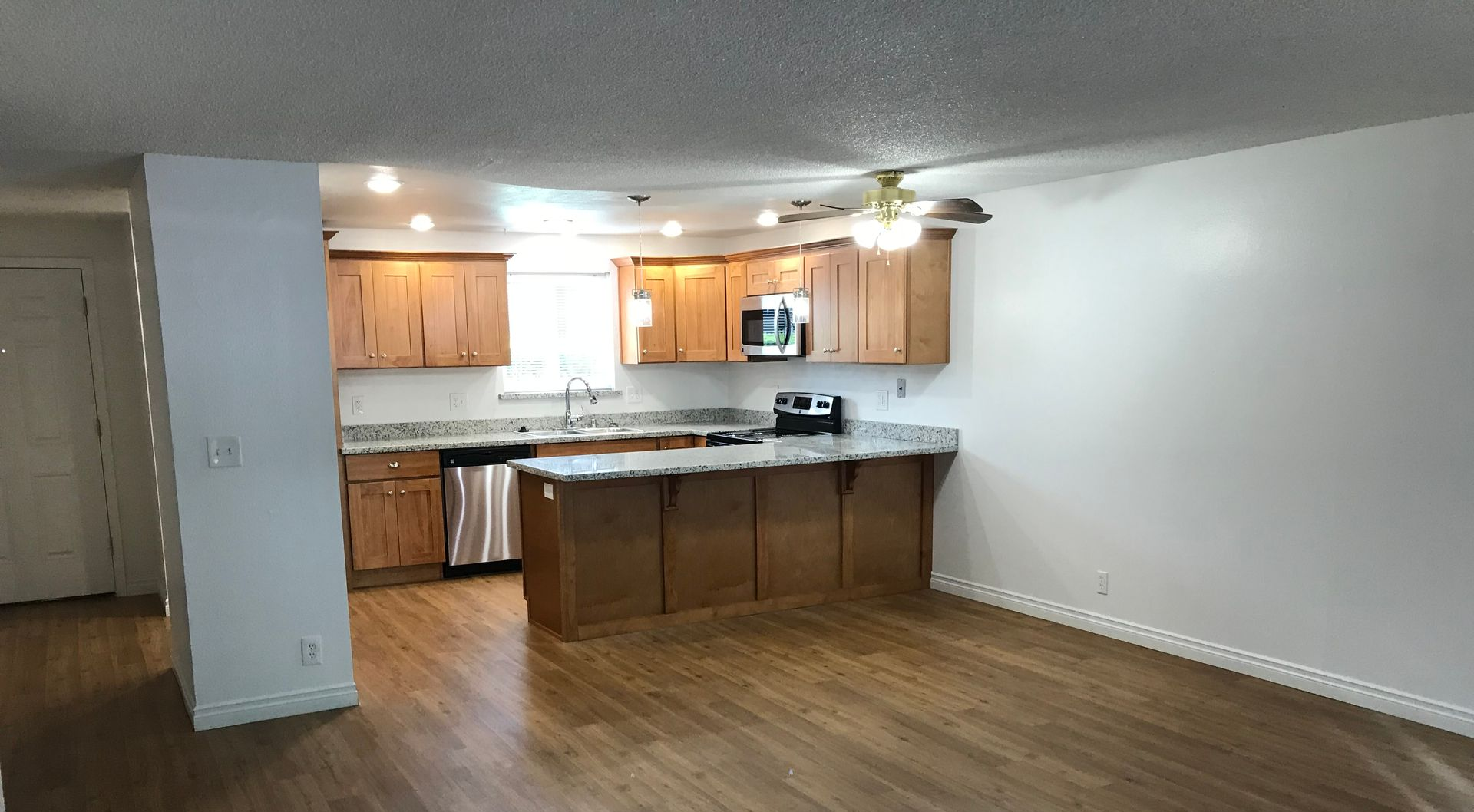 Open-concept kitchen and dining area with wood cabinets, countertops, and a stainless steel appliance.