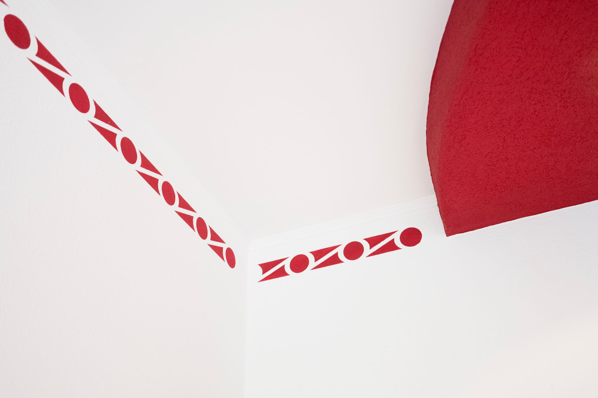 eine weiße Wand mit einem roten und weißen Muster darauf