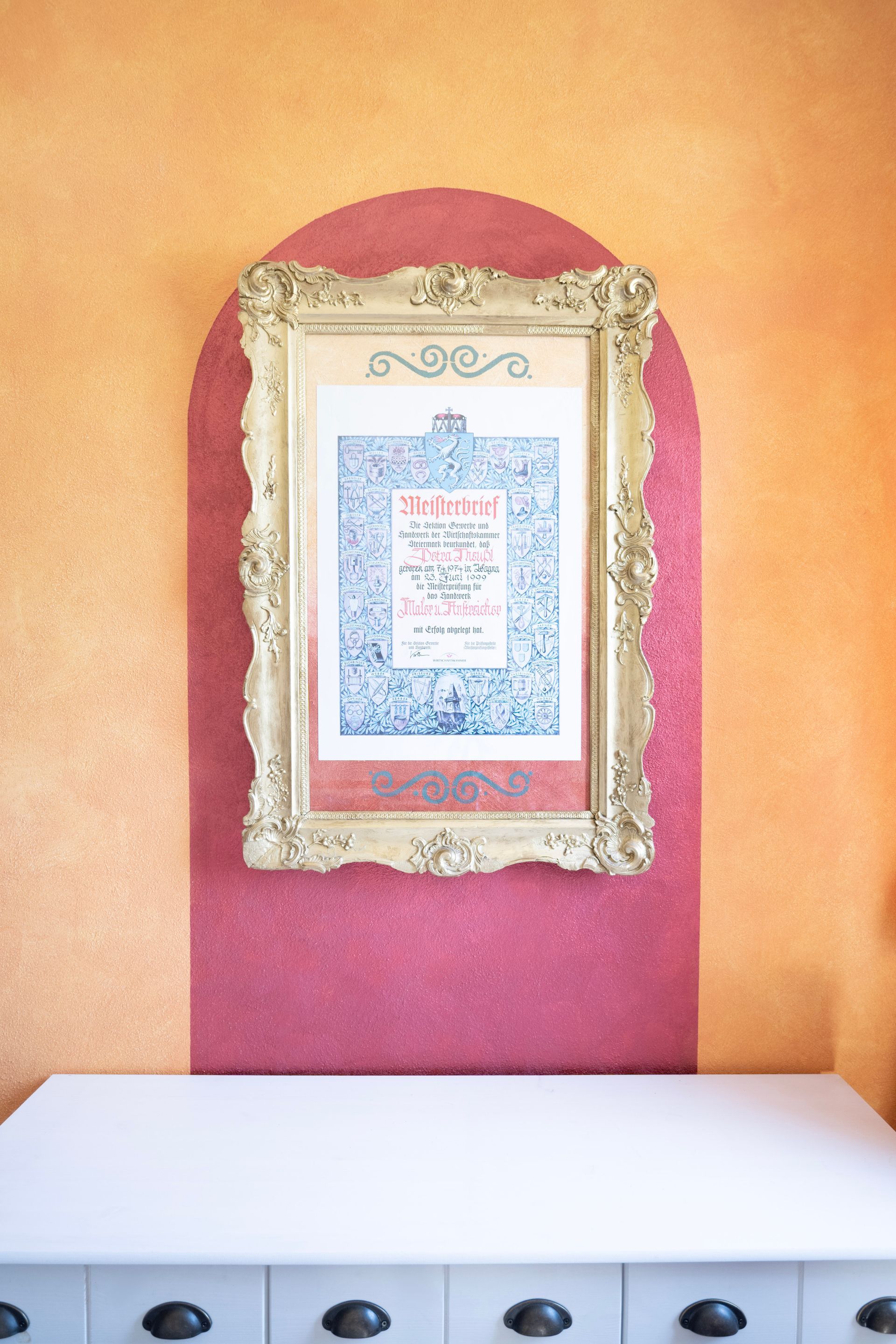 ein Gemälde in einem goldenen Rahmen hängt an einer rosa Wand