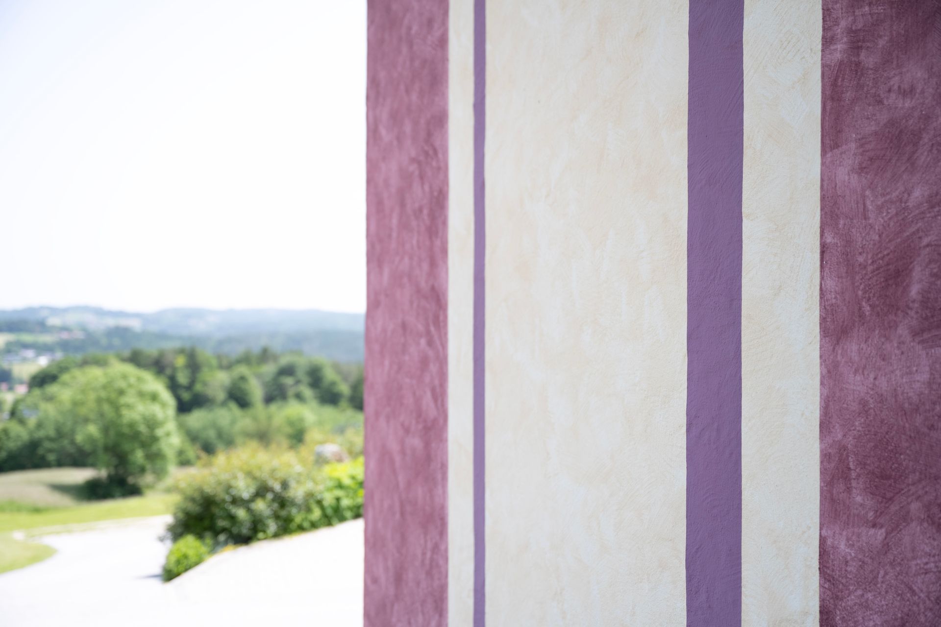 eine lila und weiß gestreifte Wand mit einem Fenster dahinter