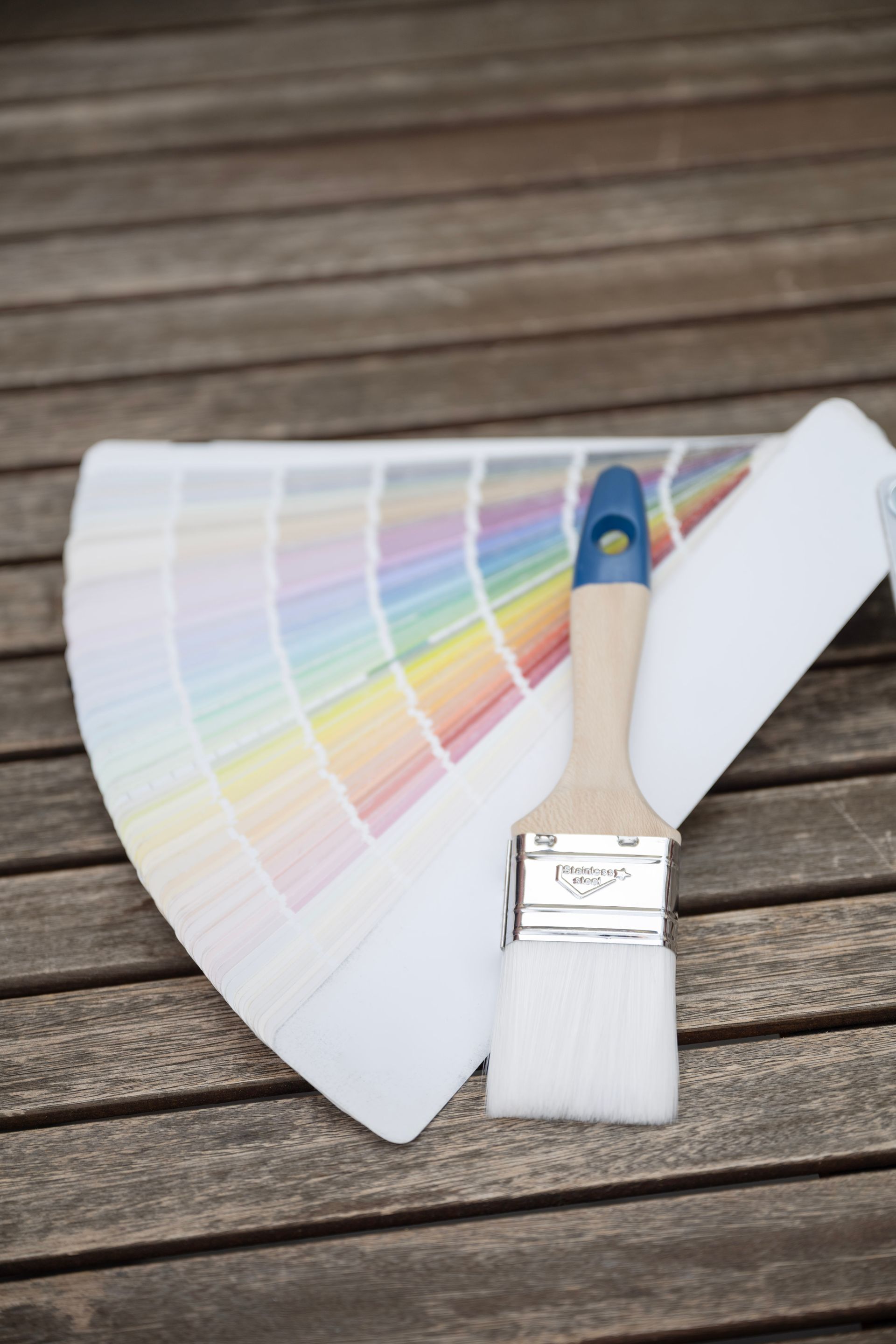 ein Pinsel liegt neben einer Farbpalette auf einem Holztisch