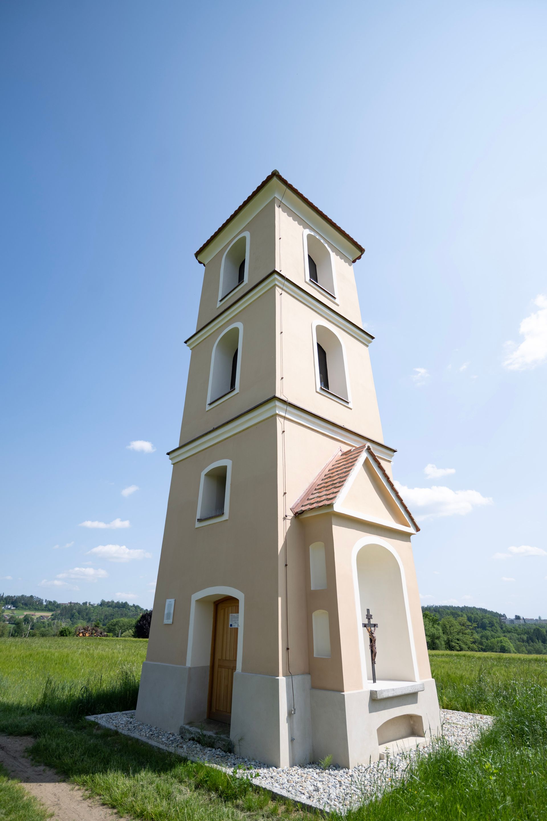 ein kleiner Turm in einem Feld mit einem Kreuz darauf