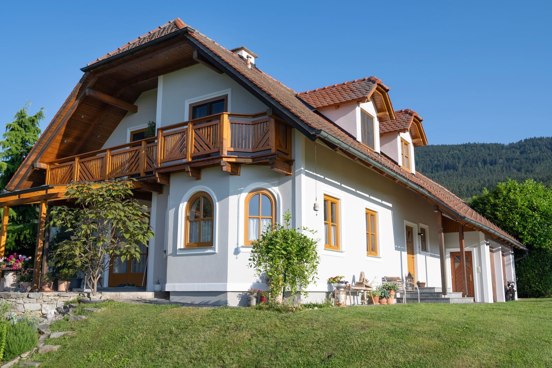 ein großes weißes Haus mit einem braunen Dach und einem Holzbalkon