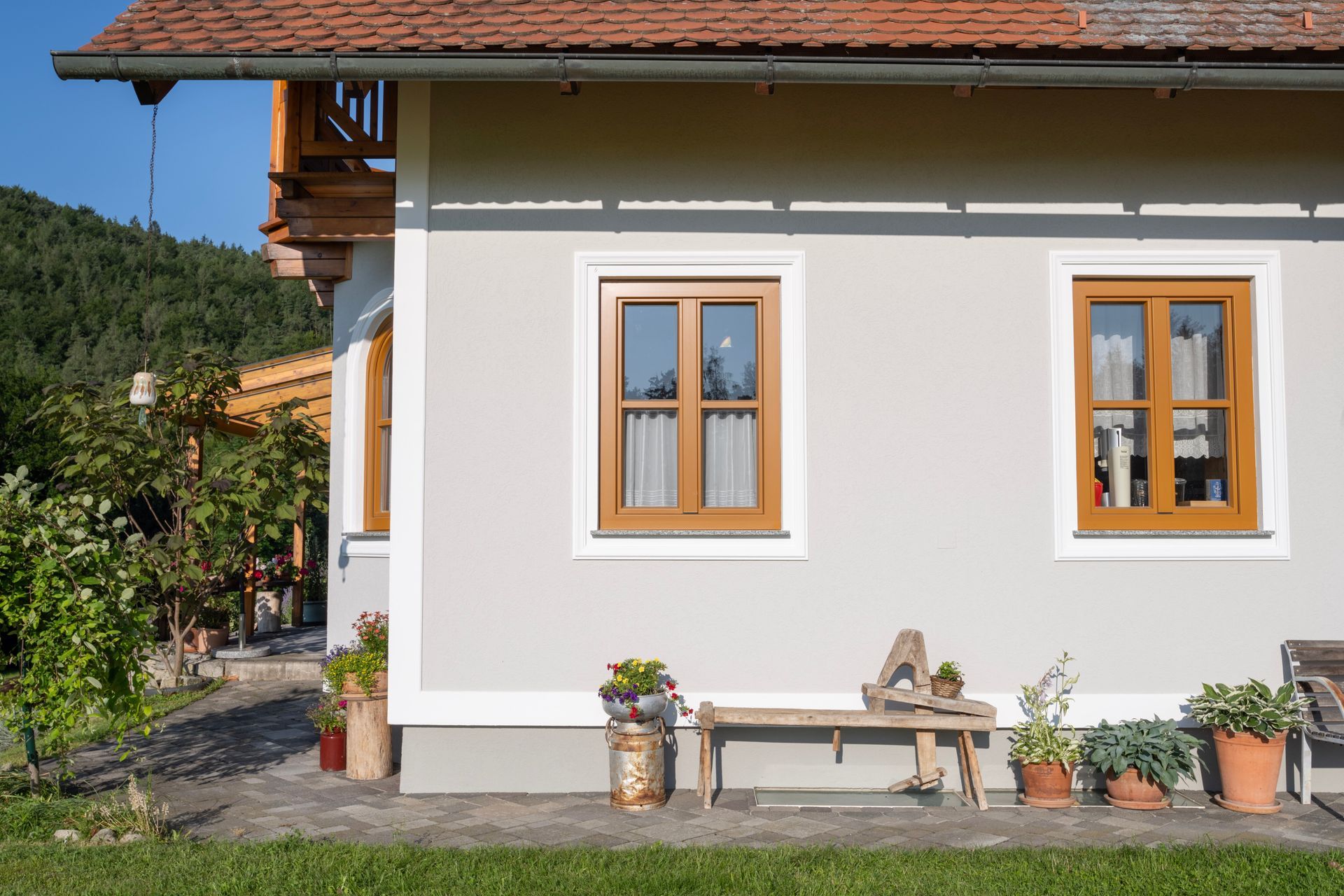 ein weißes Haus mit braunen Fenstern und einer Bank davor