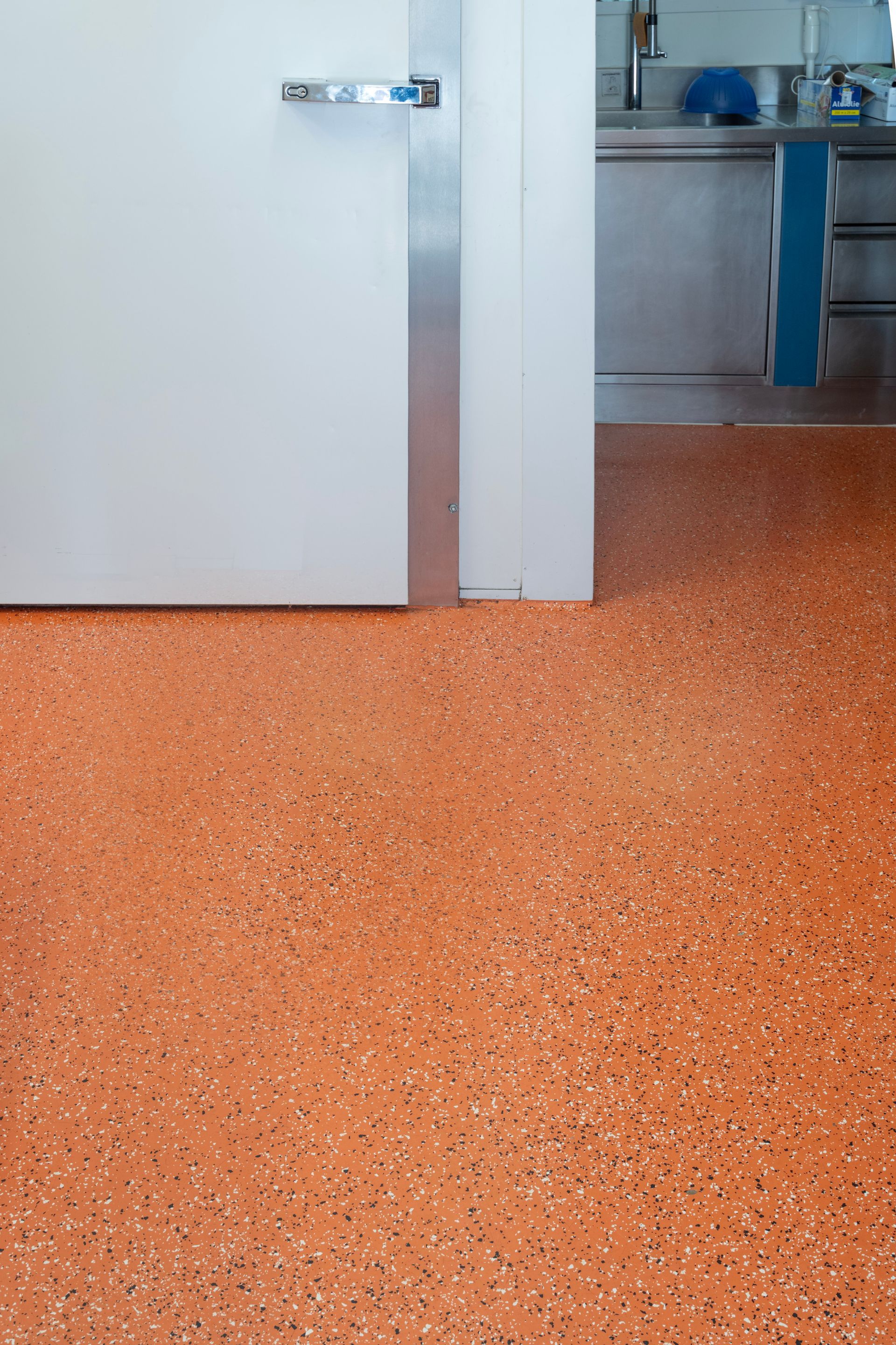 ein orangefarbener Boden in einer Küche neben einer weißen Tür