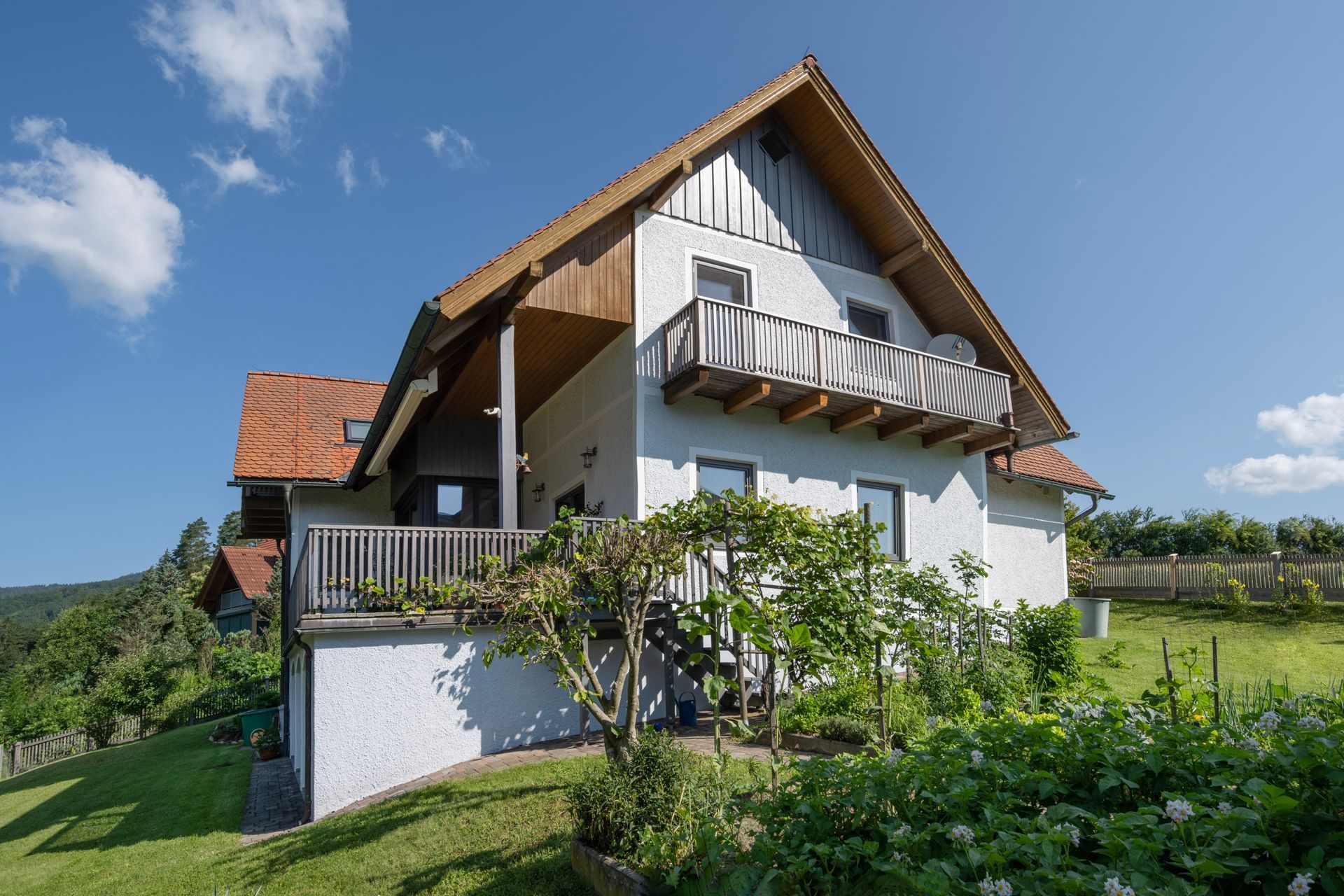 ein weißes Haus mit einem roten Dach und einem Balkon