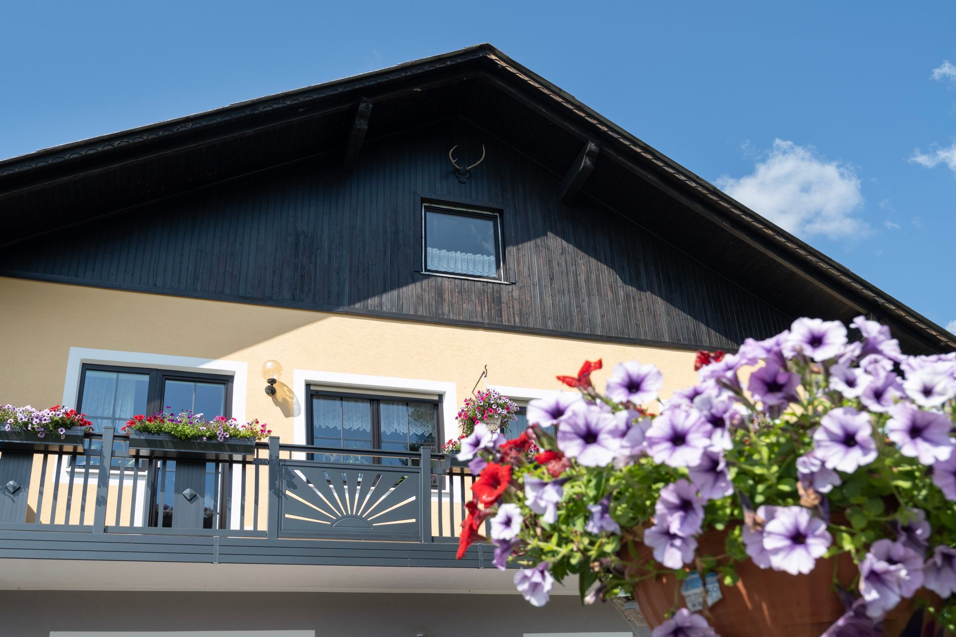 ein Balkon mit lila Blumen vor einem Haus