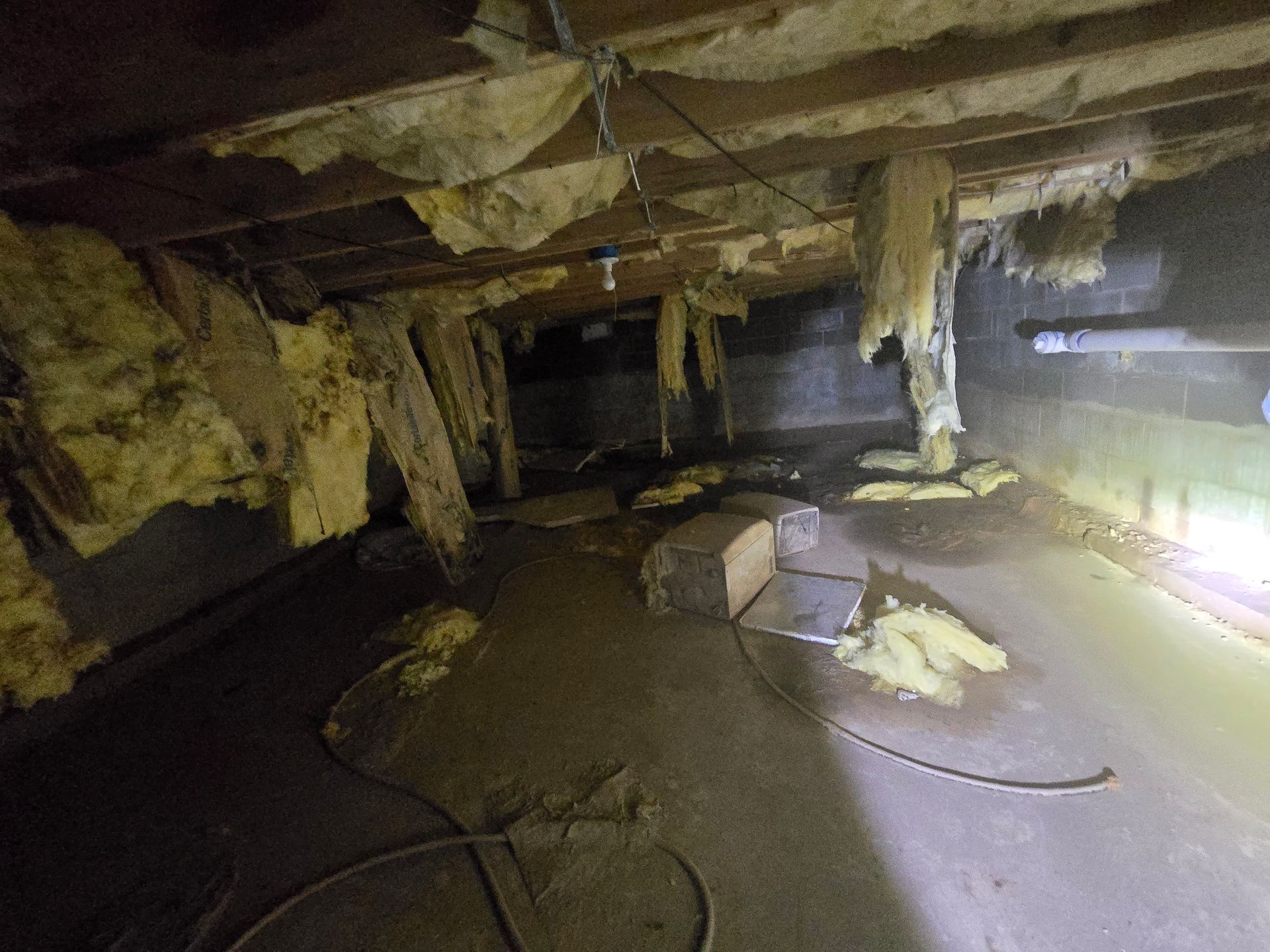 A bedroom with a bed wrapped in plastic and two fans.