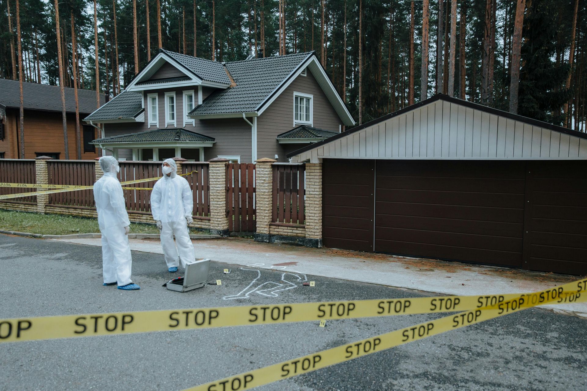 A man in a protective suit is kneeling down next to a briefcase.