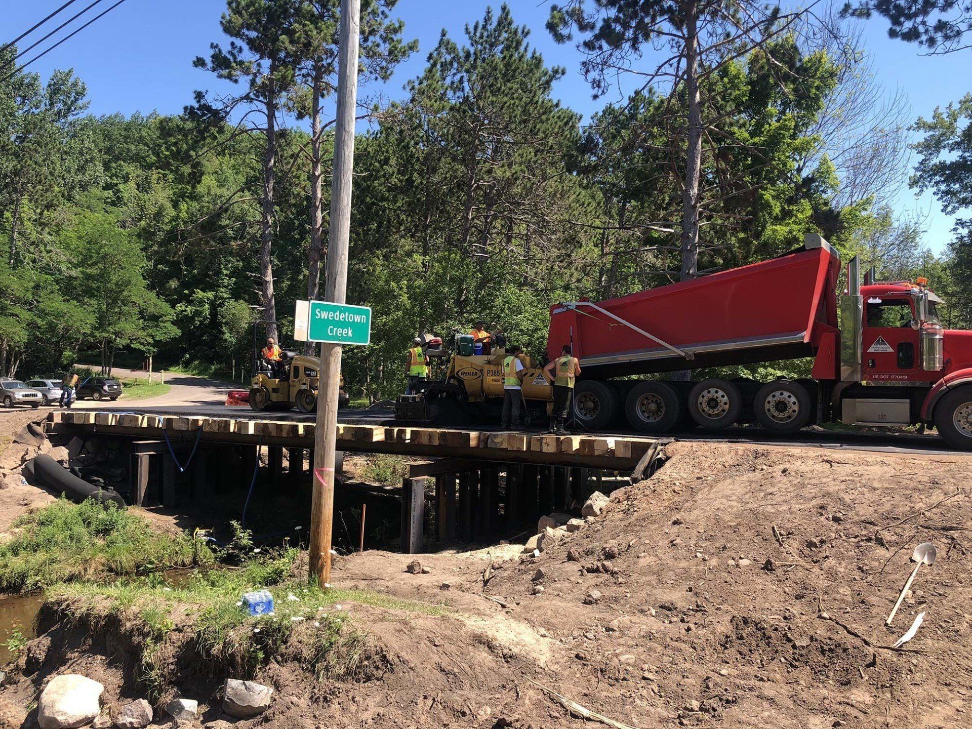 A red dump truck is driving down a dirt road.