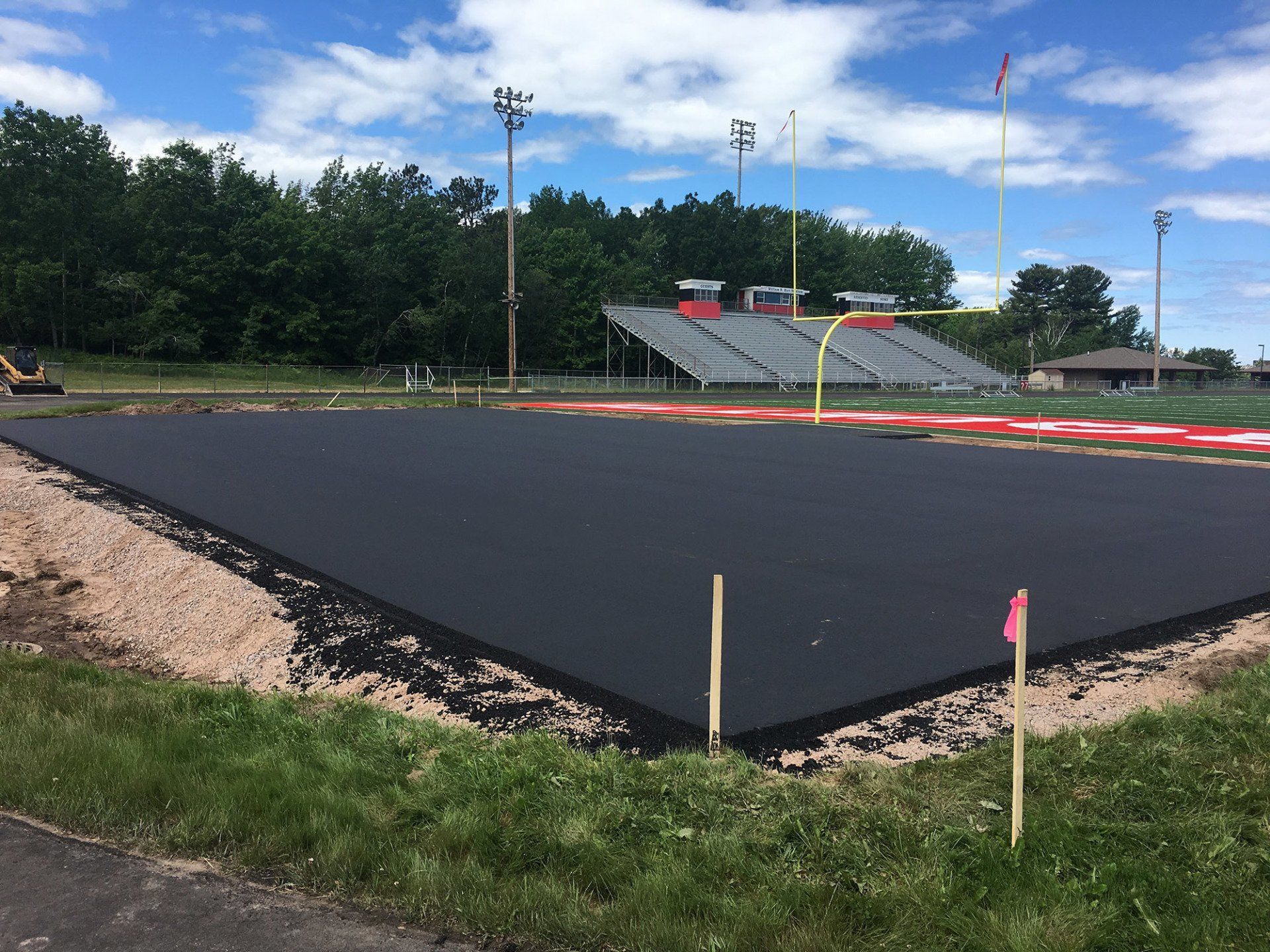 A large asphalt field is being built in front of a stadium.