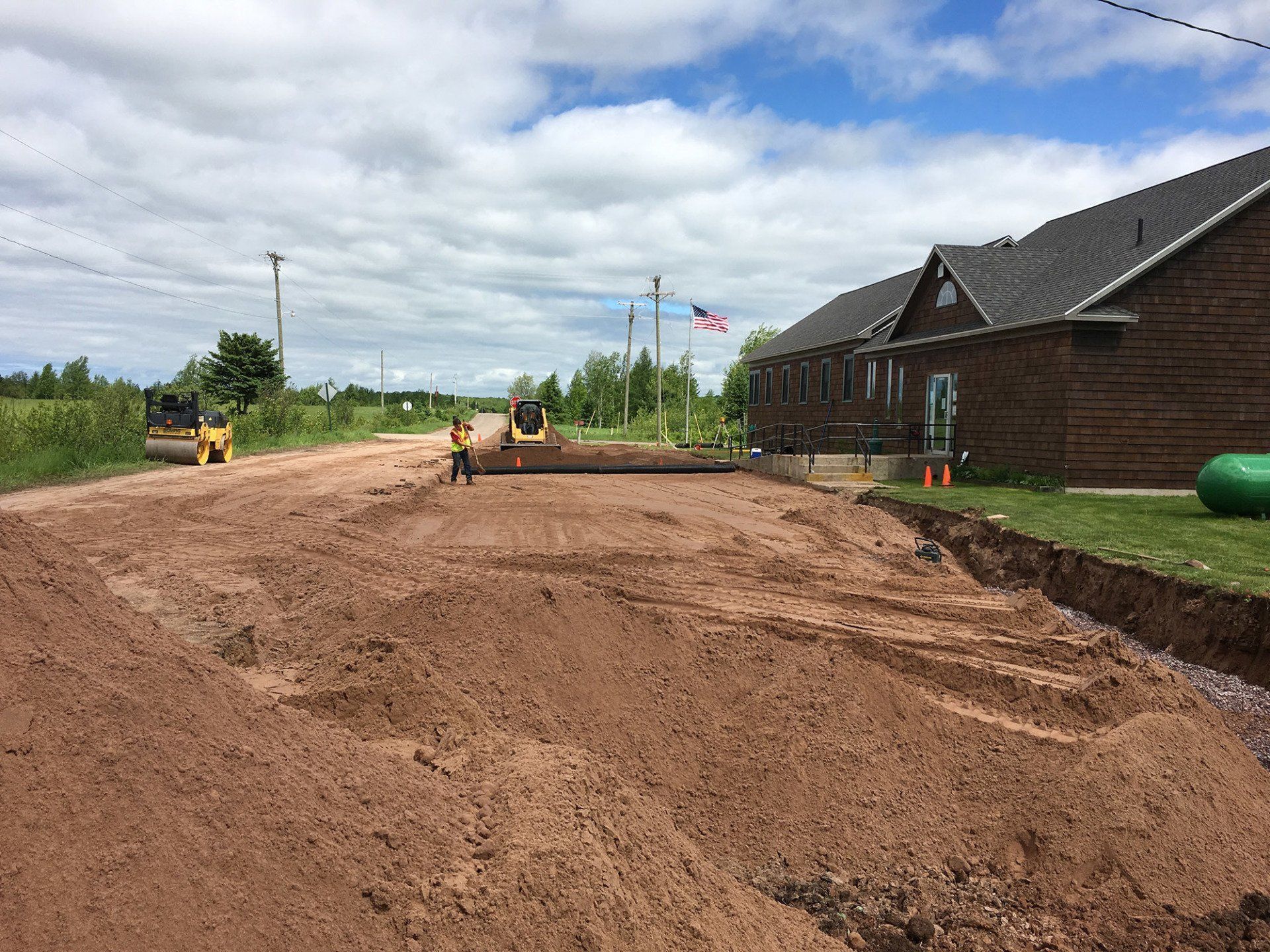 A dirt road is being paved in front of a house.
