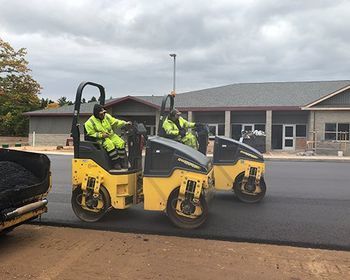 Two rollers are being used to spread asphalt on a road.