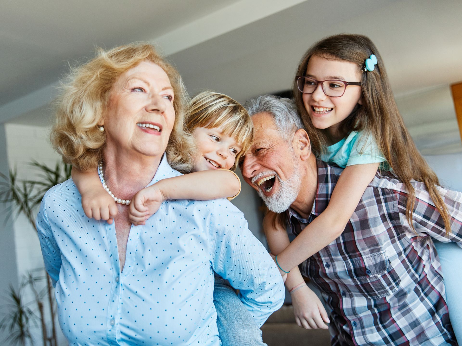 Grandparents with two grandchildren laughing, indoors.