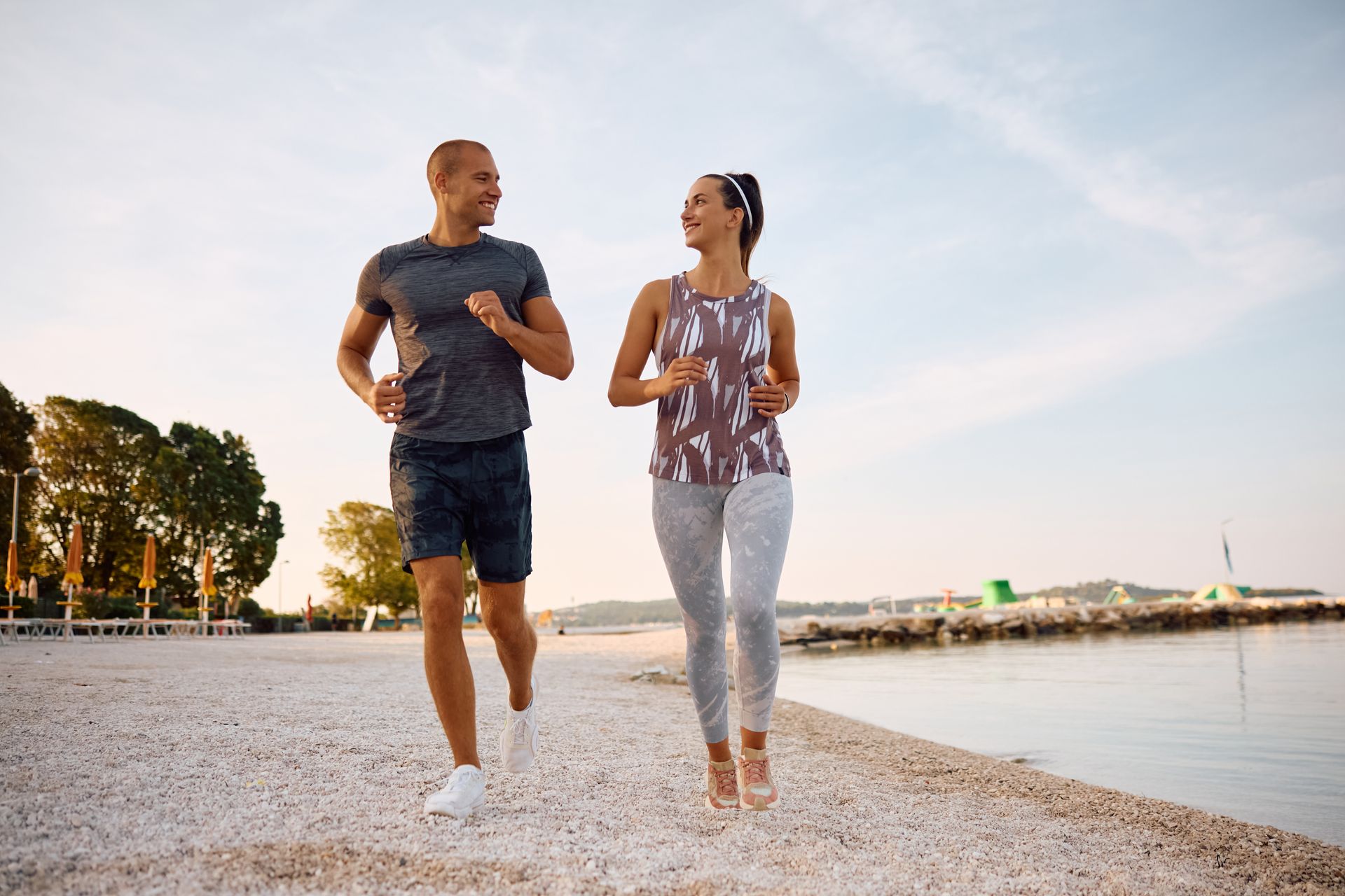 Man and woman running on a beach, smiling at each other.