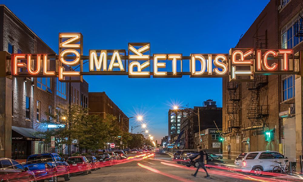 A full market district sign hangs over a busy city street