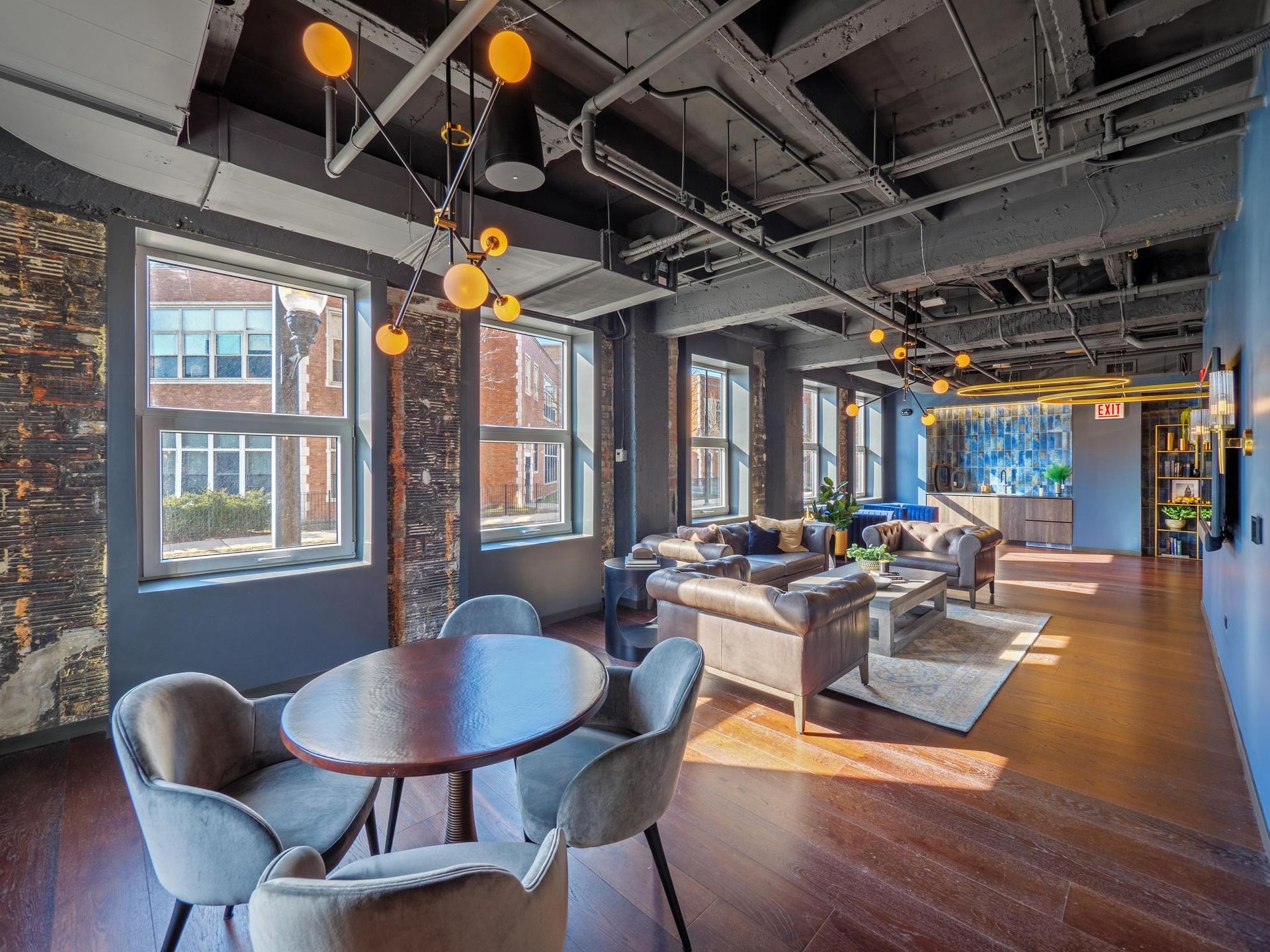 wood table with four chairs by a sitting area in  The Thompson at Fulton Market's apartment resident lounge