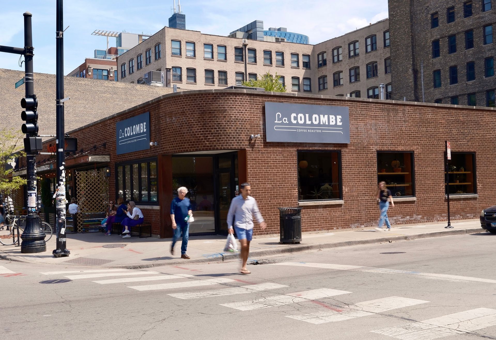 People crossing the street in front of the La Colombe building