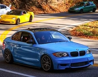 A blue car is driving down a road next to a yellow car.